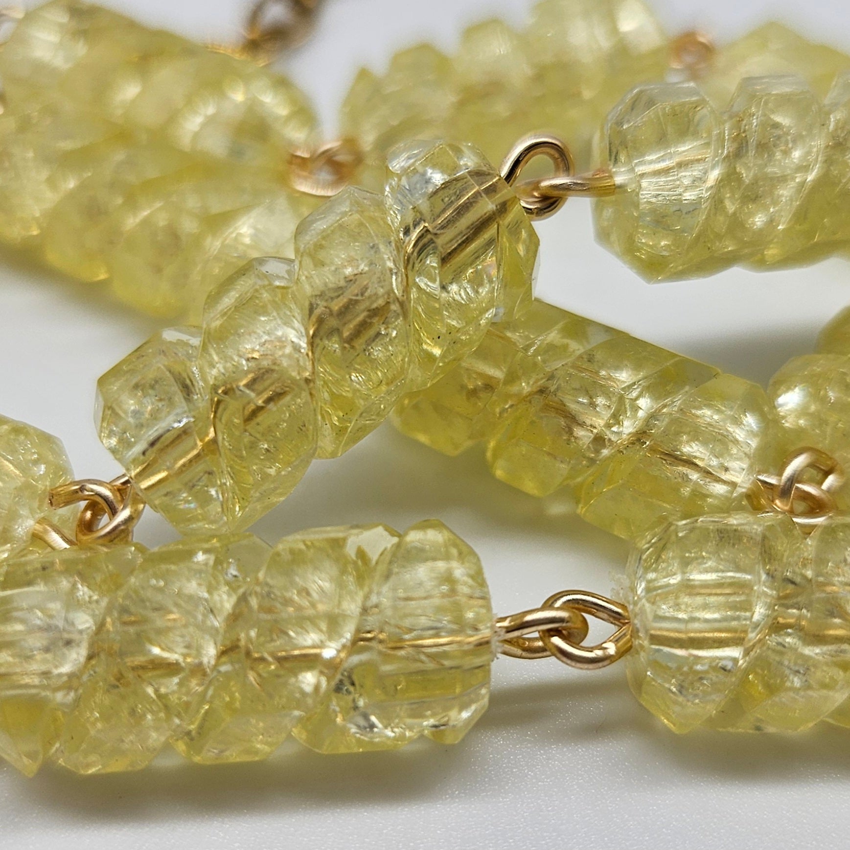 Close-up of a yellow beaded necklace with gold wires on a white background