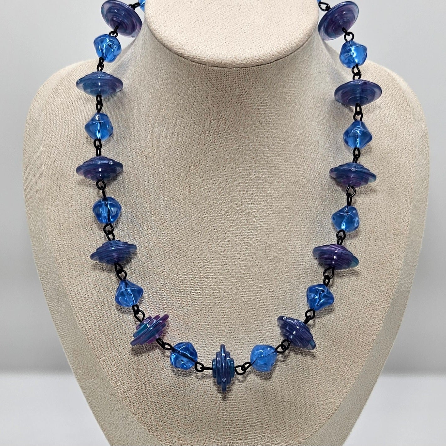 Necklace with blue and purple beads on a beige bust