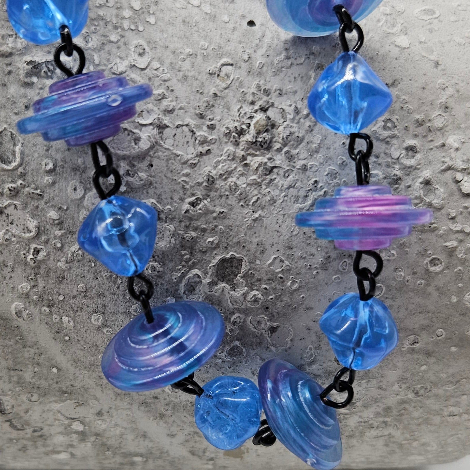 Necklace with blue and purple lucite beads on a textured surface