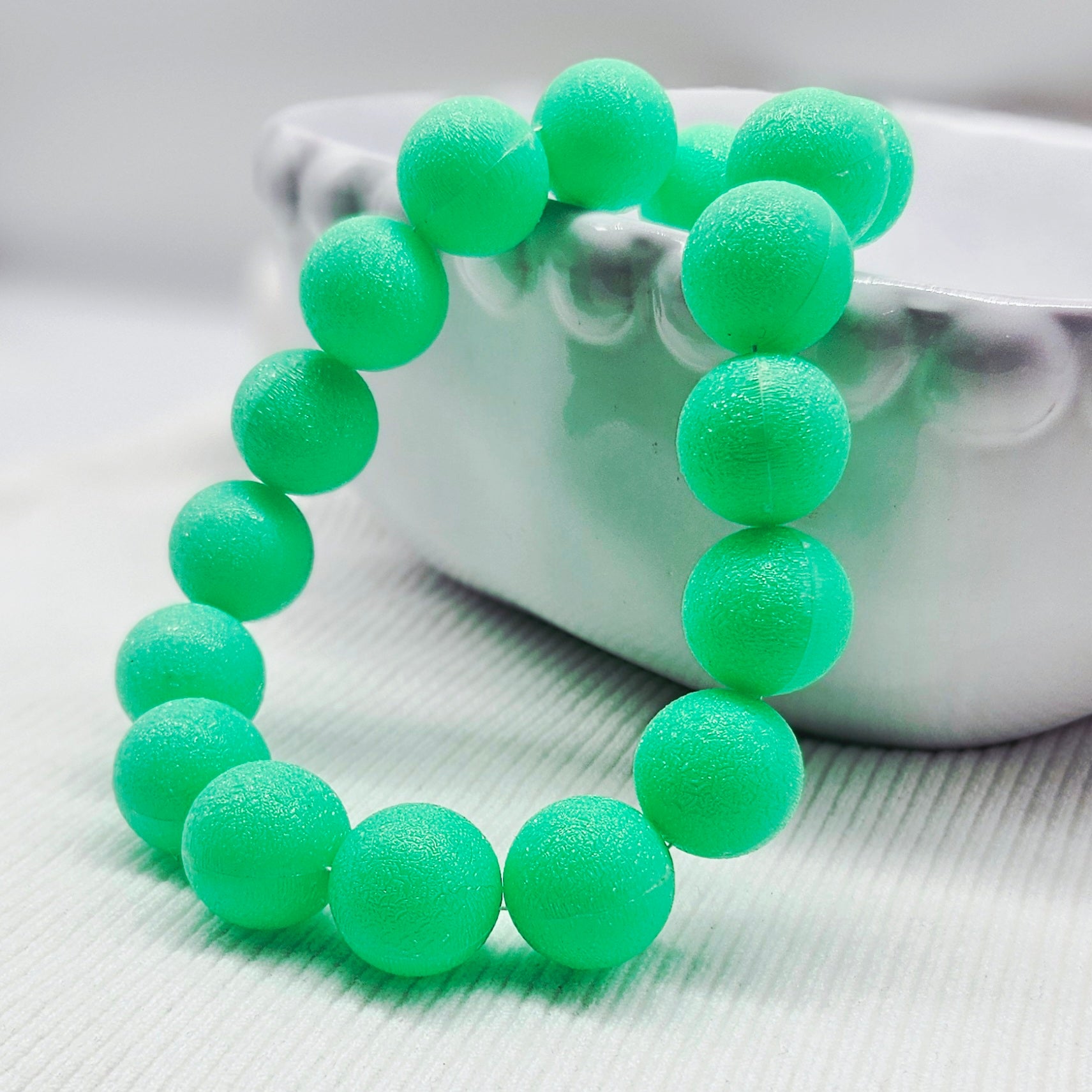 Green beaded necklace on a textured surface with a blurred background