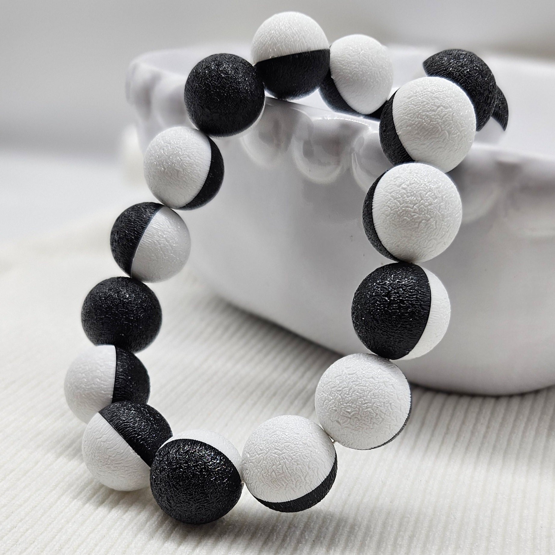 Black and white beaded necklace laid on a white bowl.