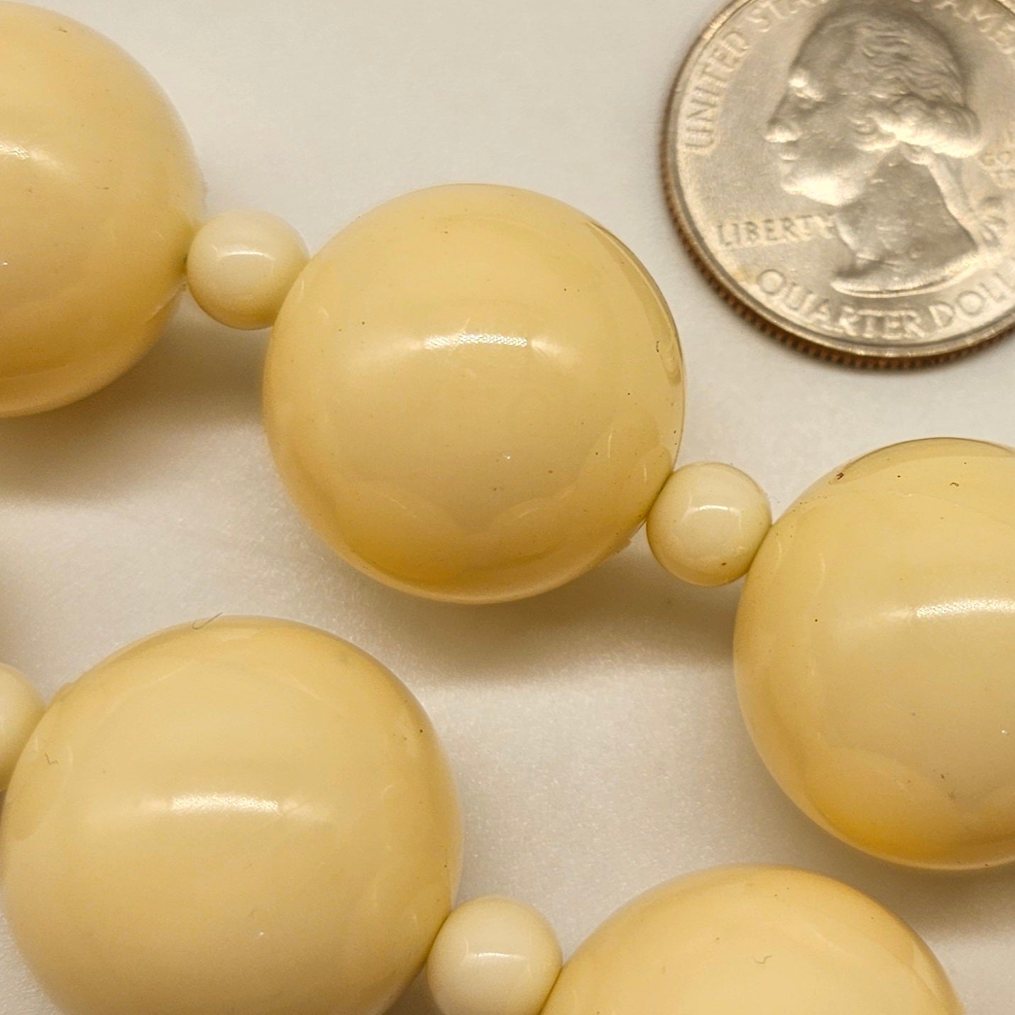 Beige beads with a quarter for size comparison on a white background