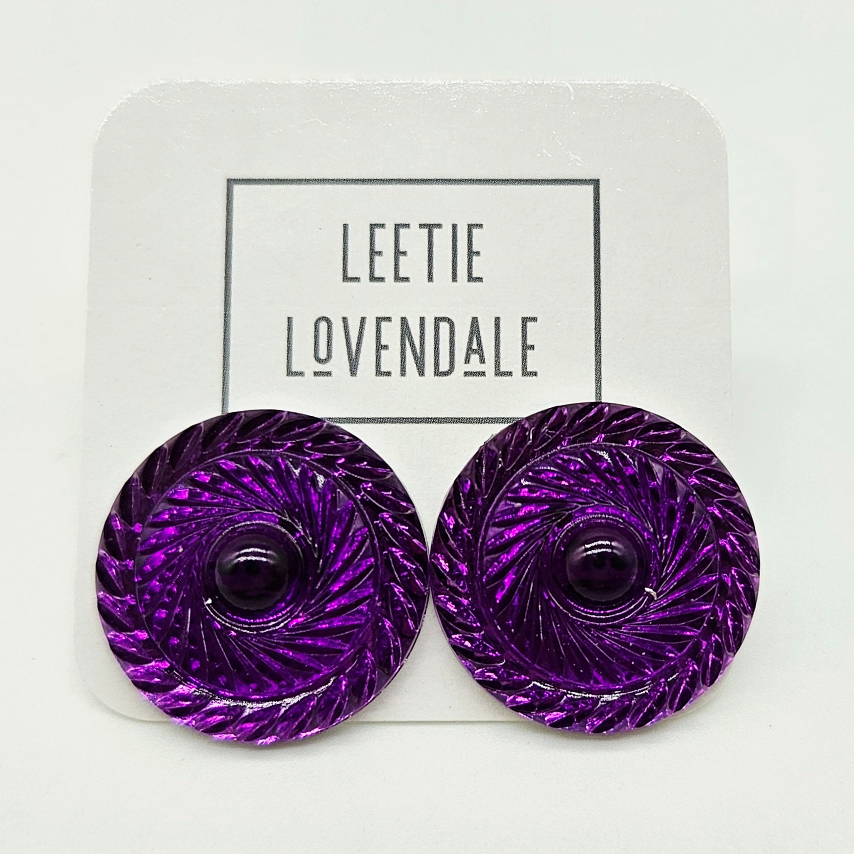 Purple circular earrings on a white card with &