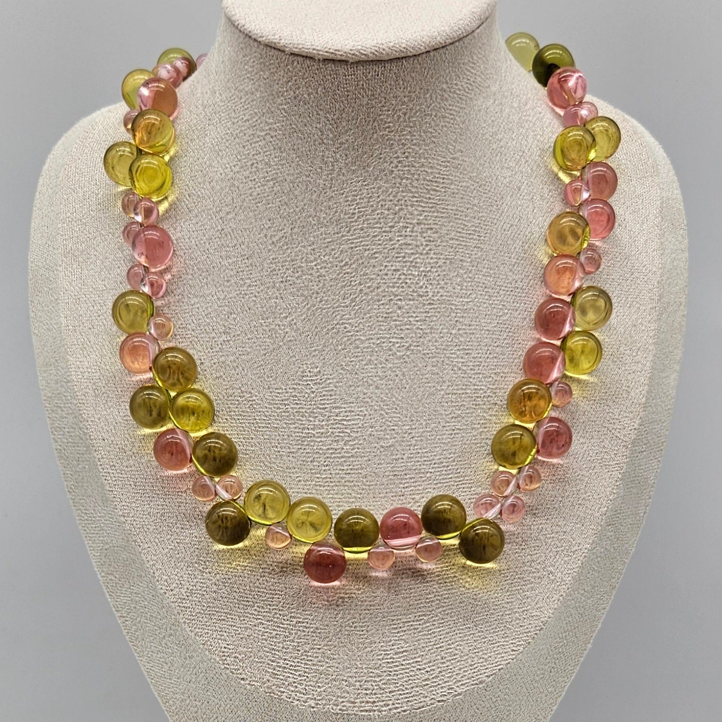 Necklace with multicolored beads on a mannequin bust against a gray background