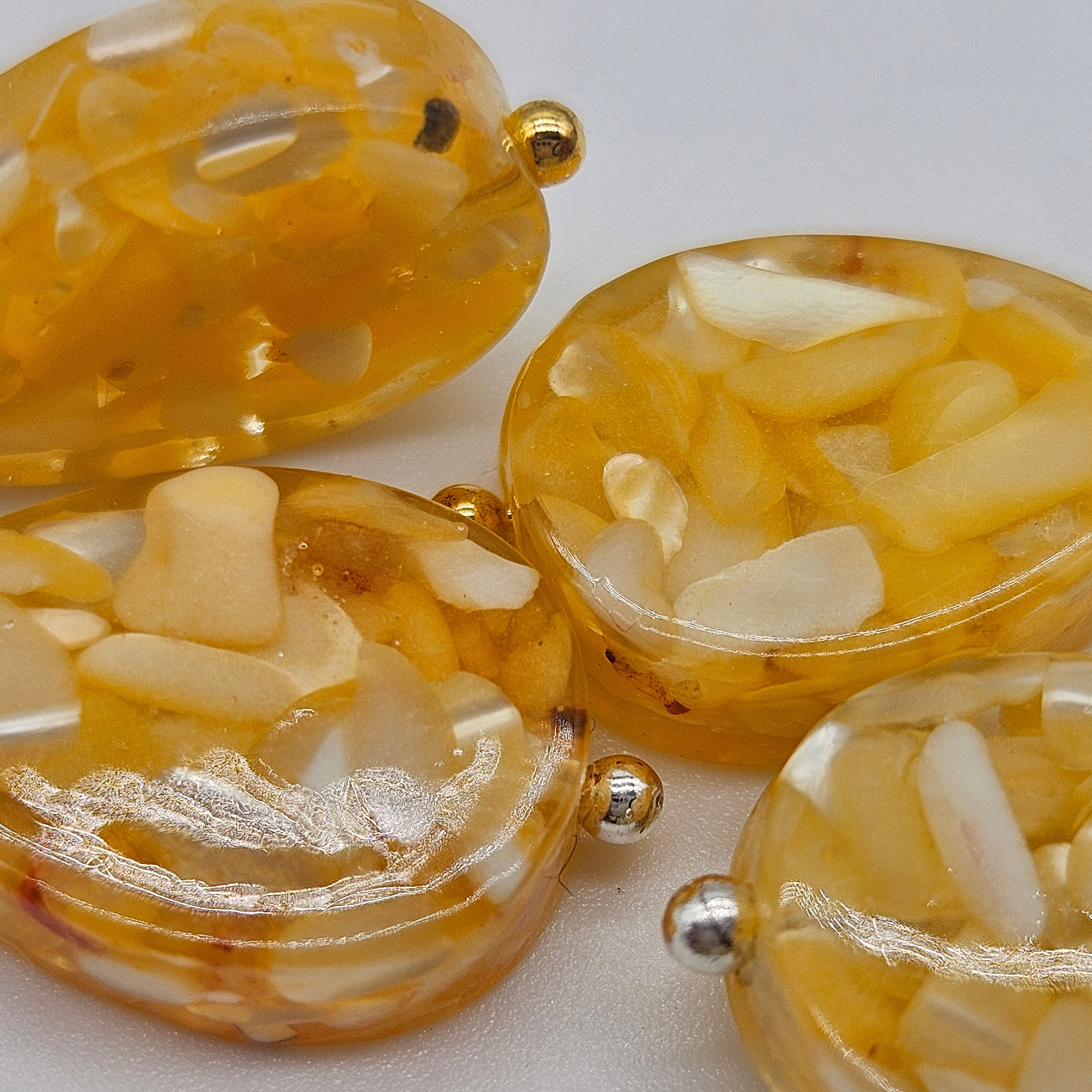 Close-up of amber-colored earrings with gold accents on a light background