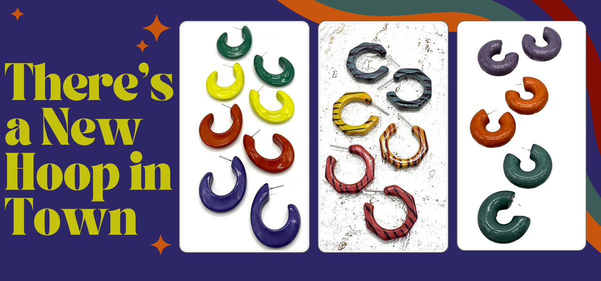 Promotional graphic with three panels showing colorful horseshoe-shaped hoop earrings in different colors and finishes, set against a dark purple background with rainbow arcs and yellow text reading 'There's a New Hoop in Town.'.
