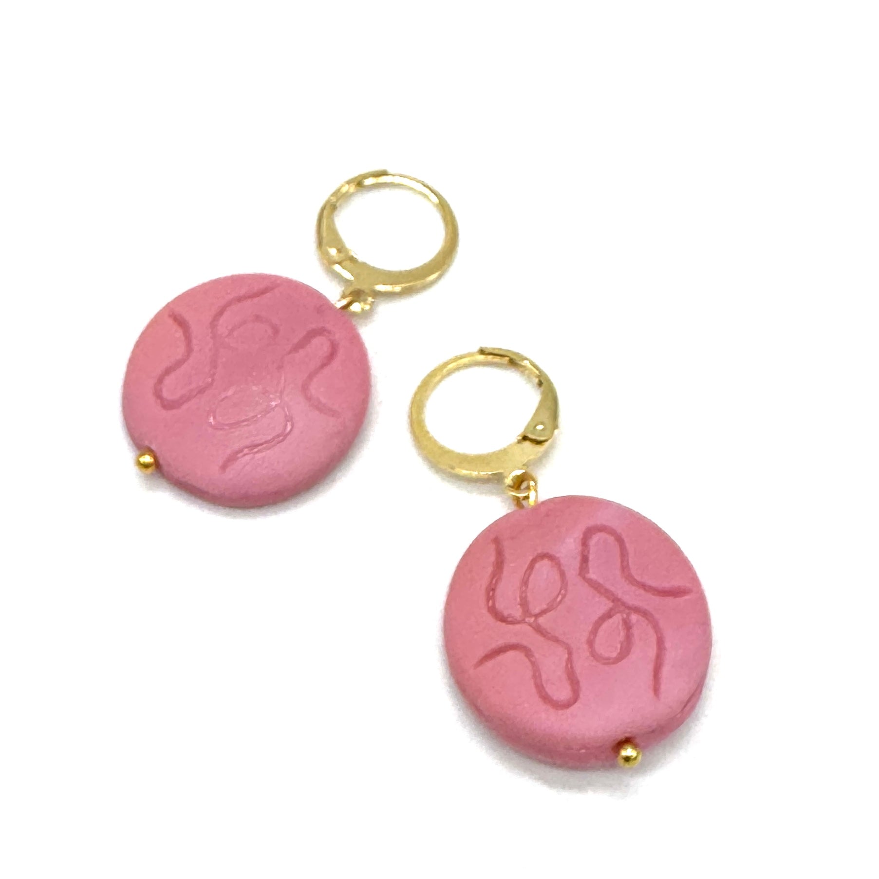 Pink earrings with gold hooks on a white background