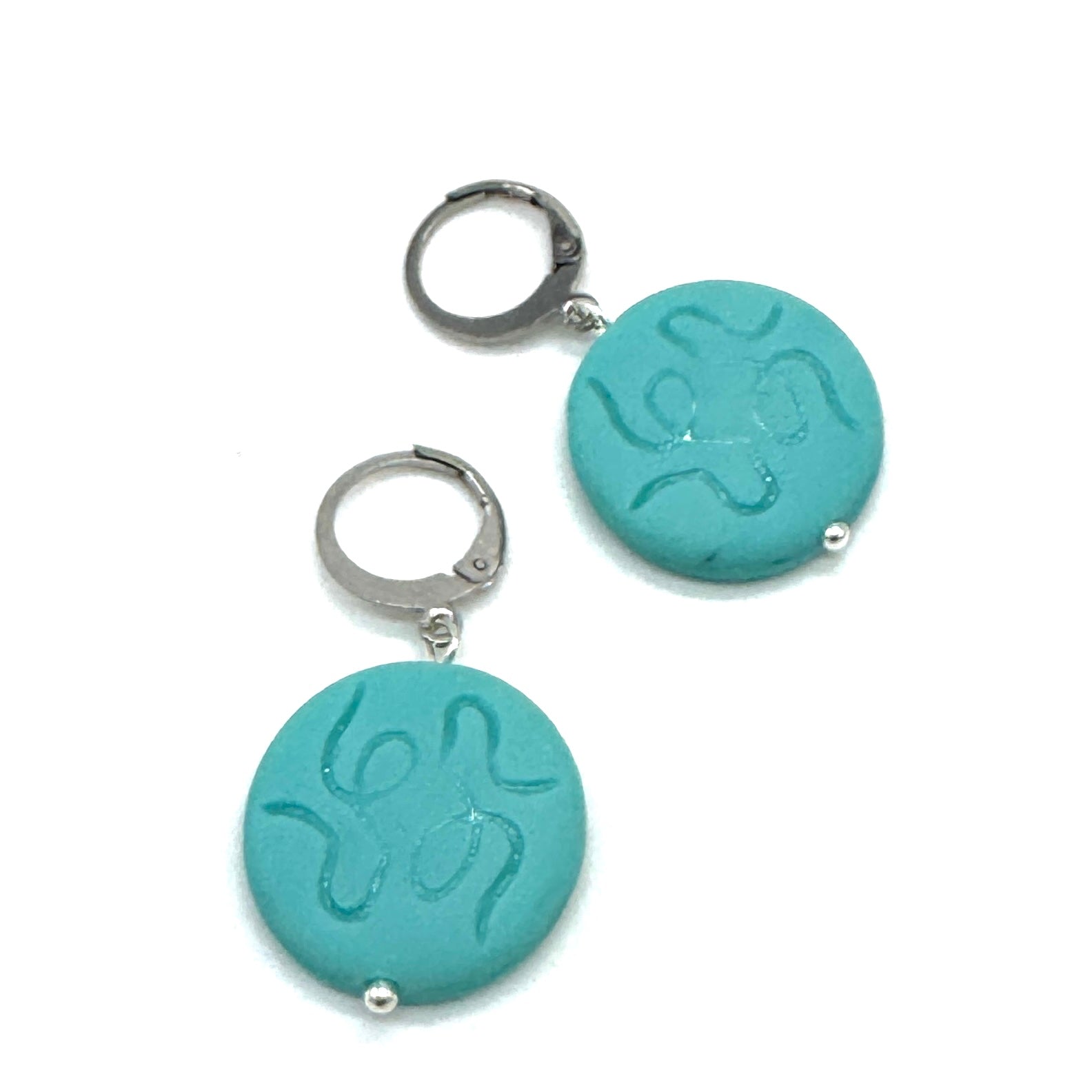 Pair of turquoise earrings with silver hooks on a white background