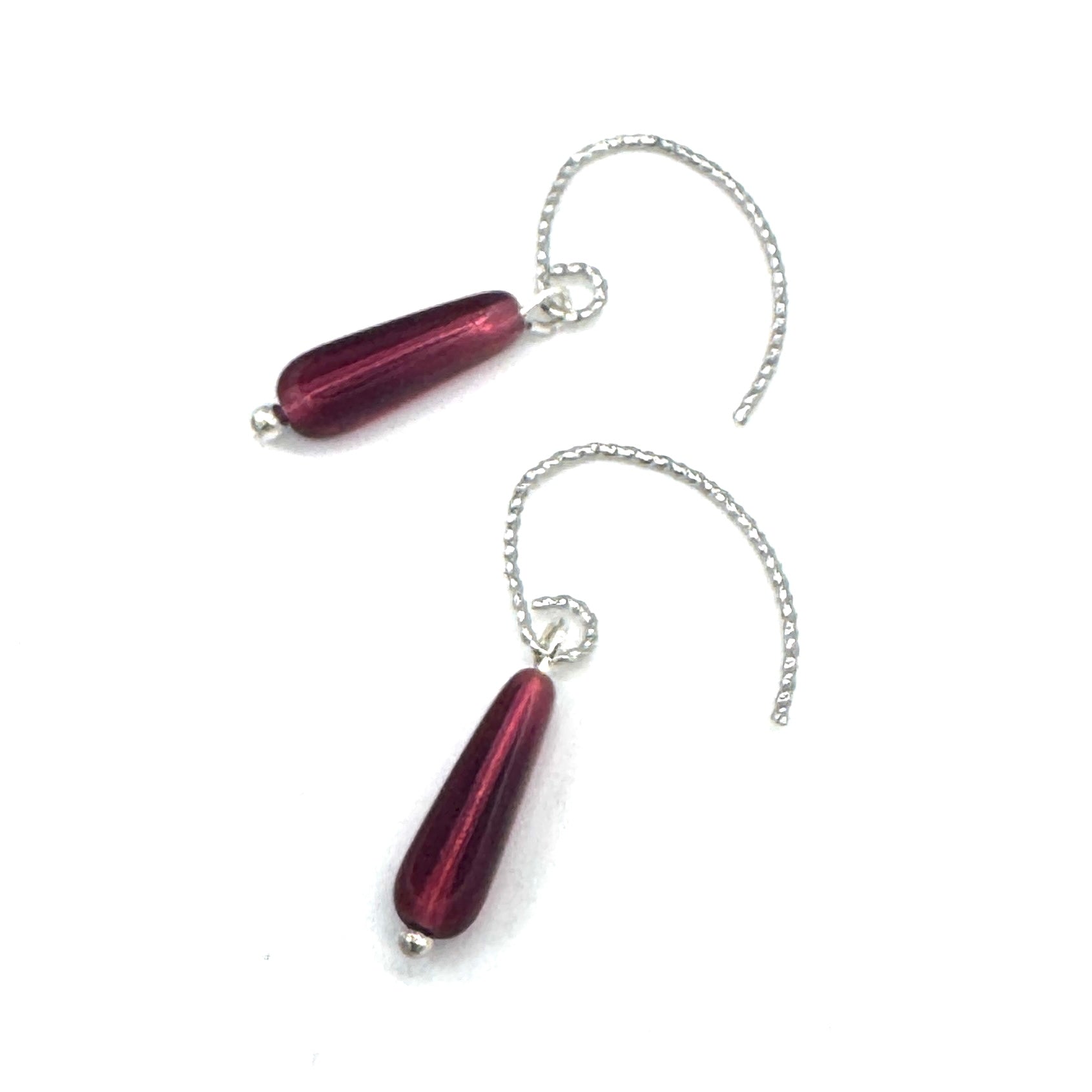 Pair of red teardrop-shaped earrings with silver chains on a white background