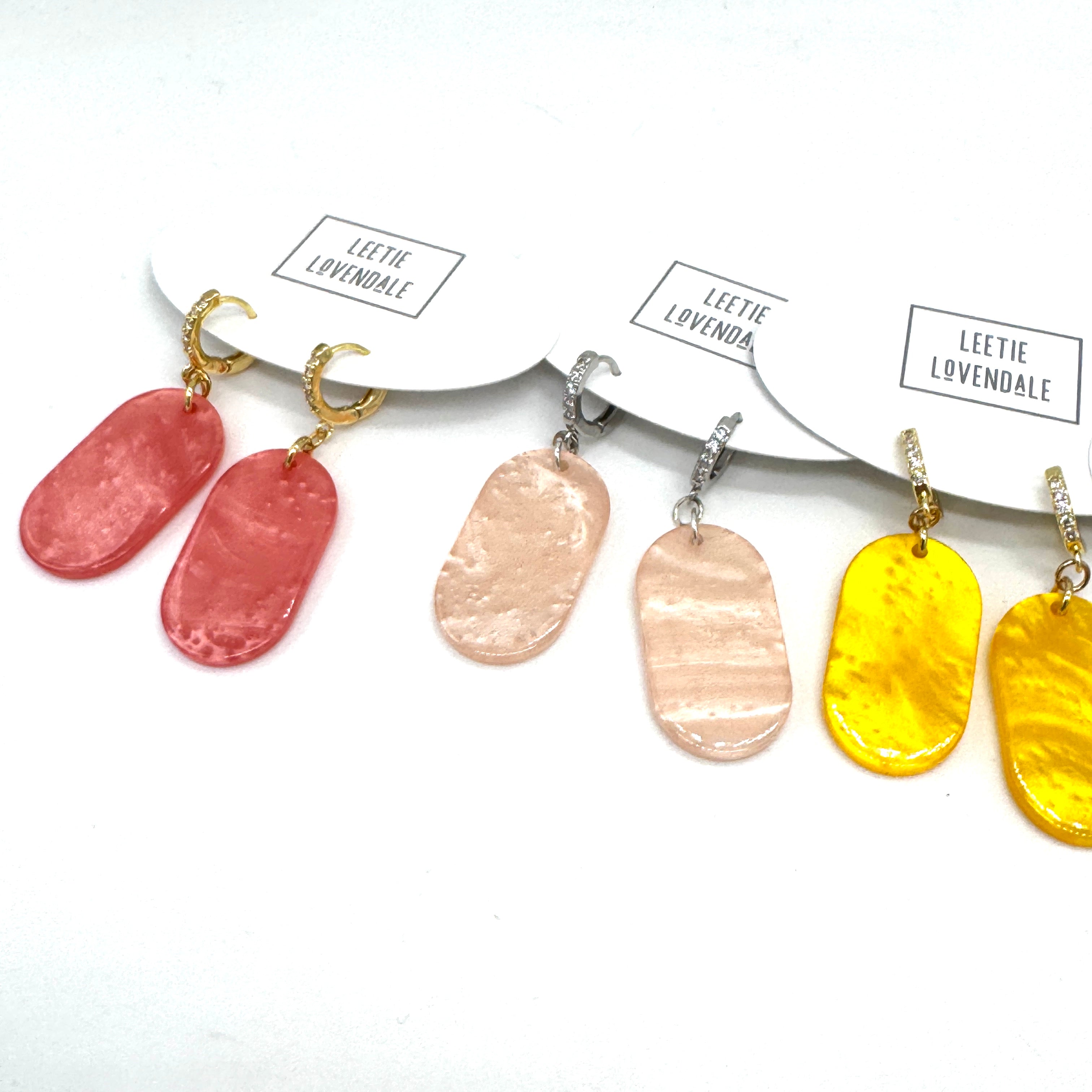 Set of earrings with different colored pendants on a white background, branded &