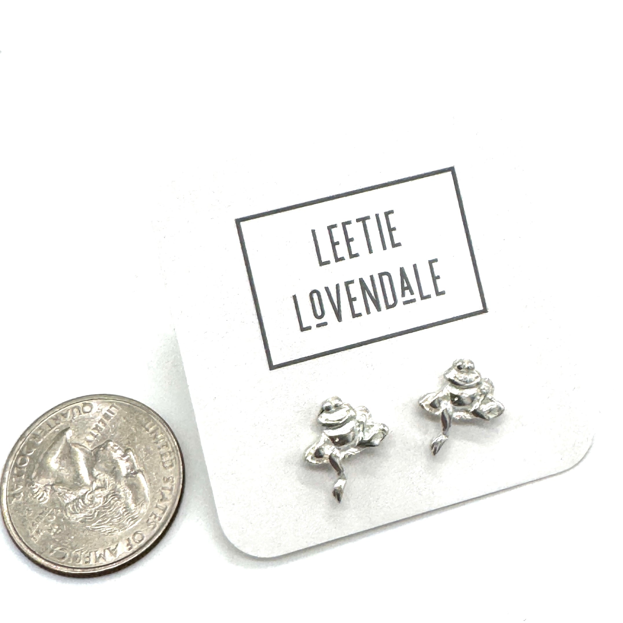 Silver frog-shaped earrings on a card with &