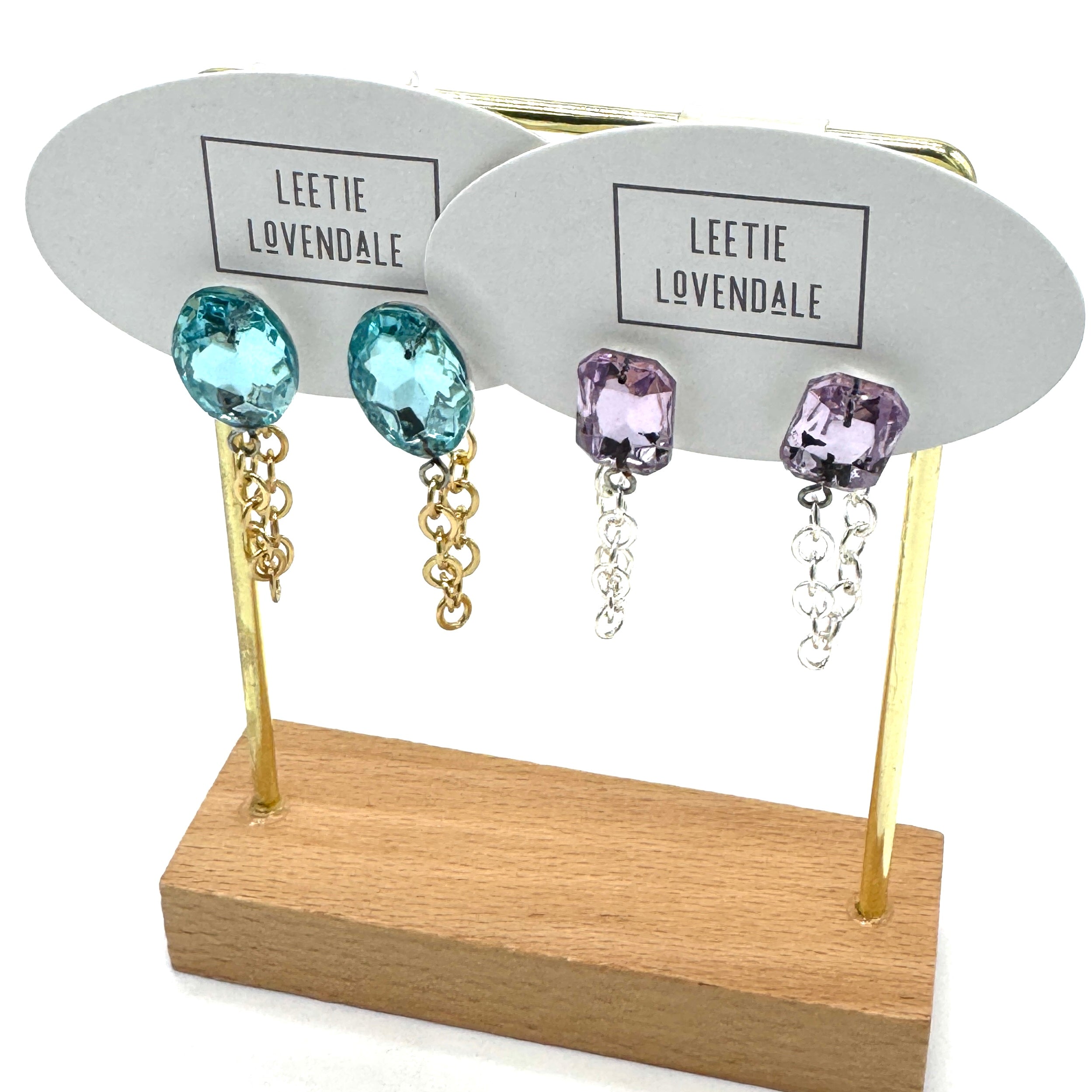 Pair of earrings with blue and purple gemstones on a display stand with &