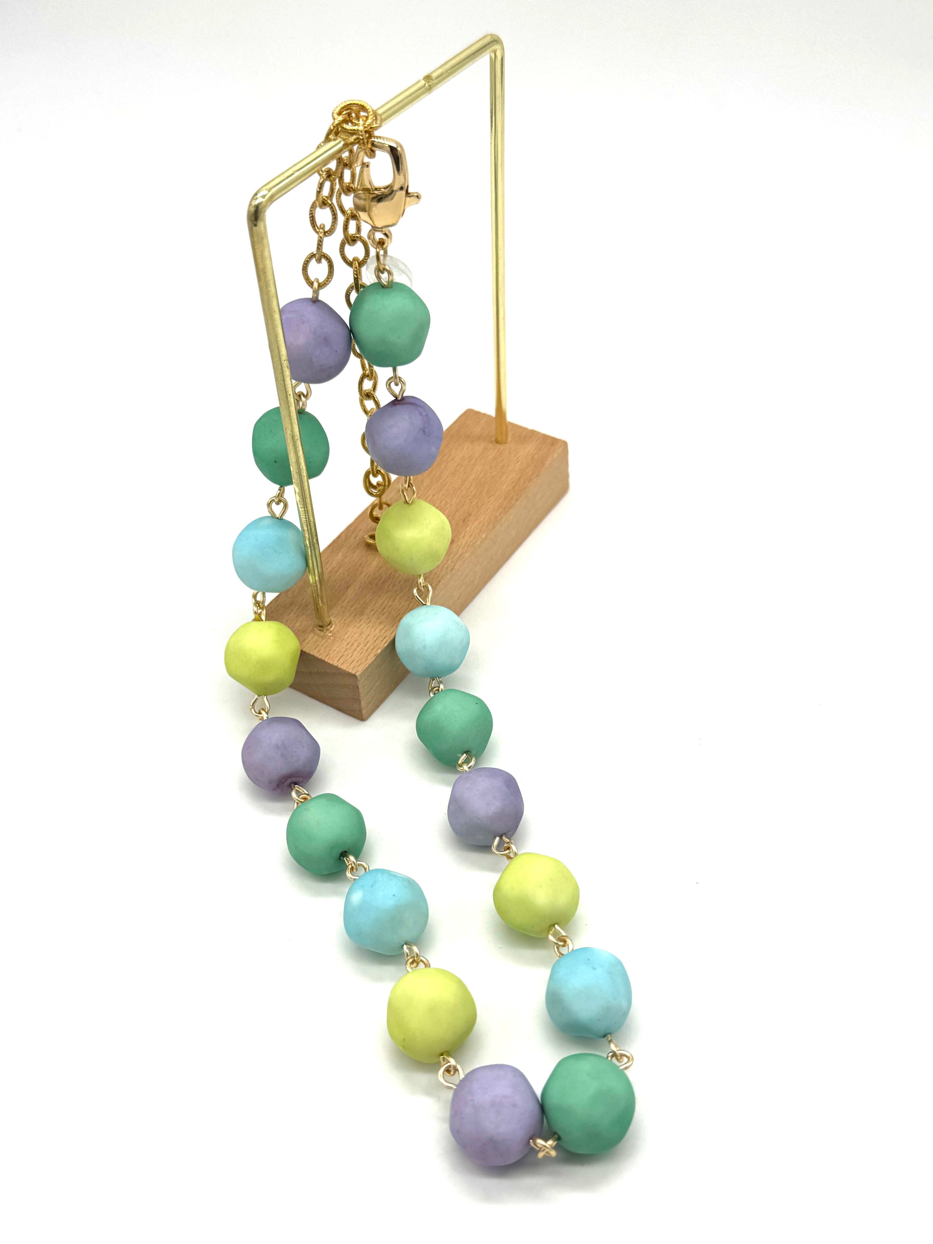 Necklace with pastel-colored beads on a wooden stand against a white background