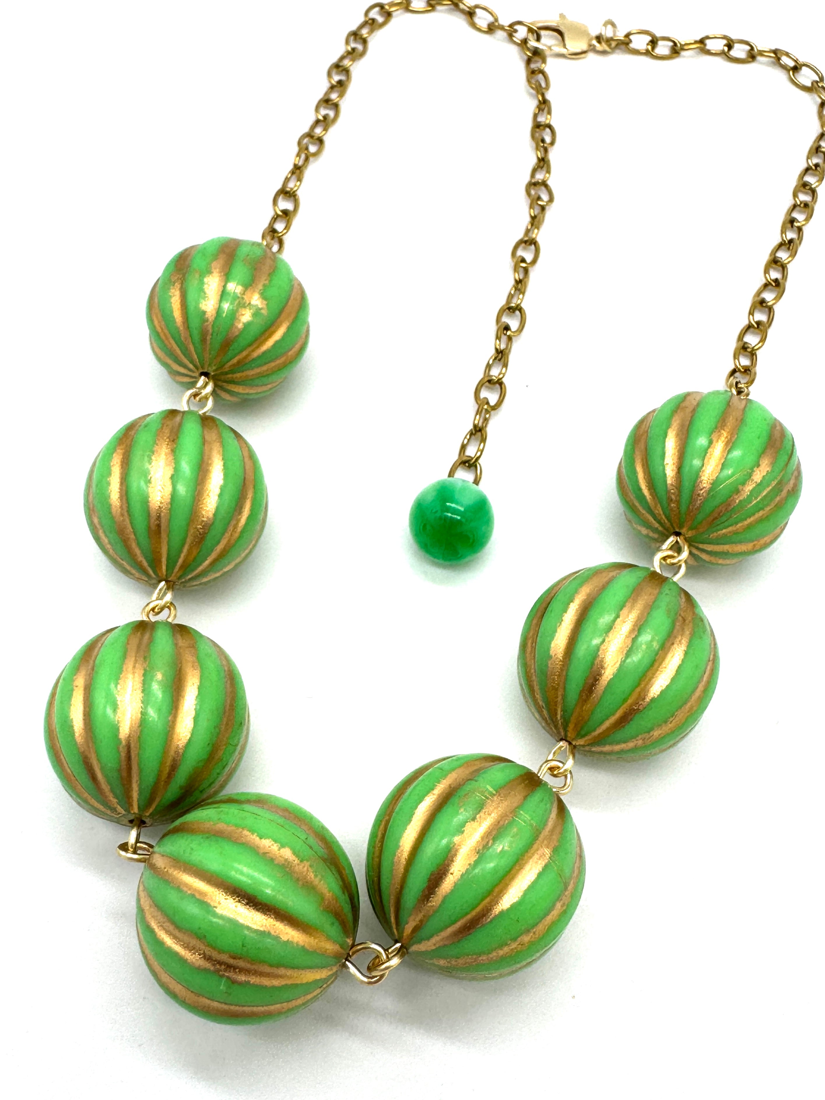 Necklace with green and gold striped beads on a white background