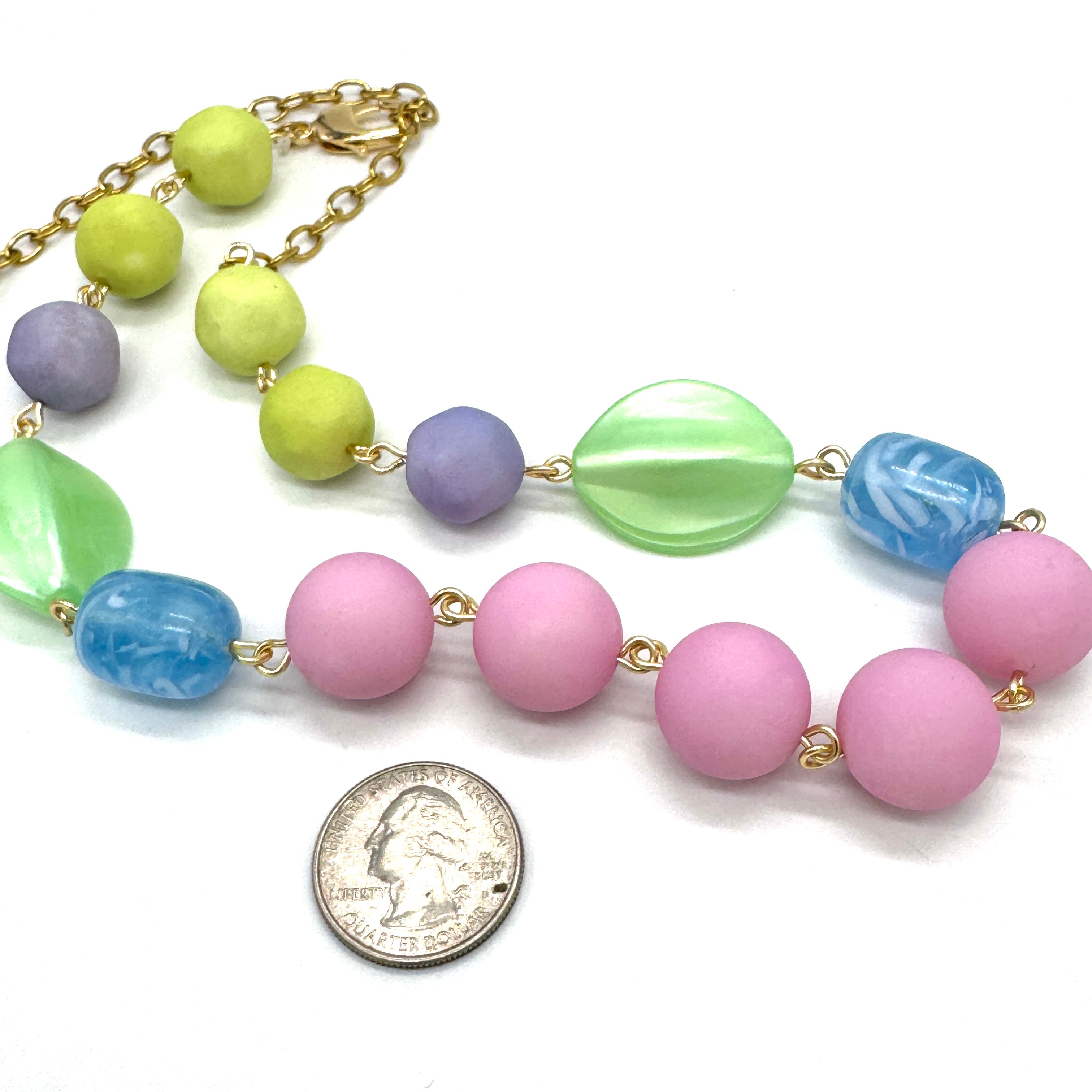 Colorful beaded necklace with a quarter for scale on a white background