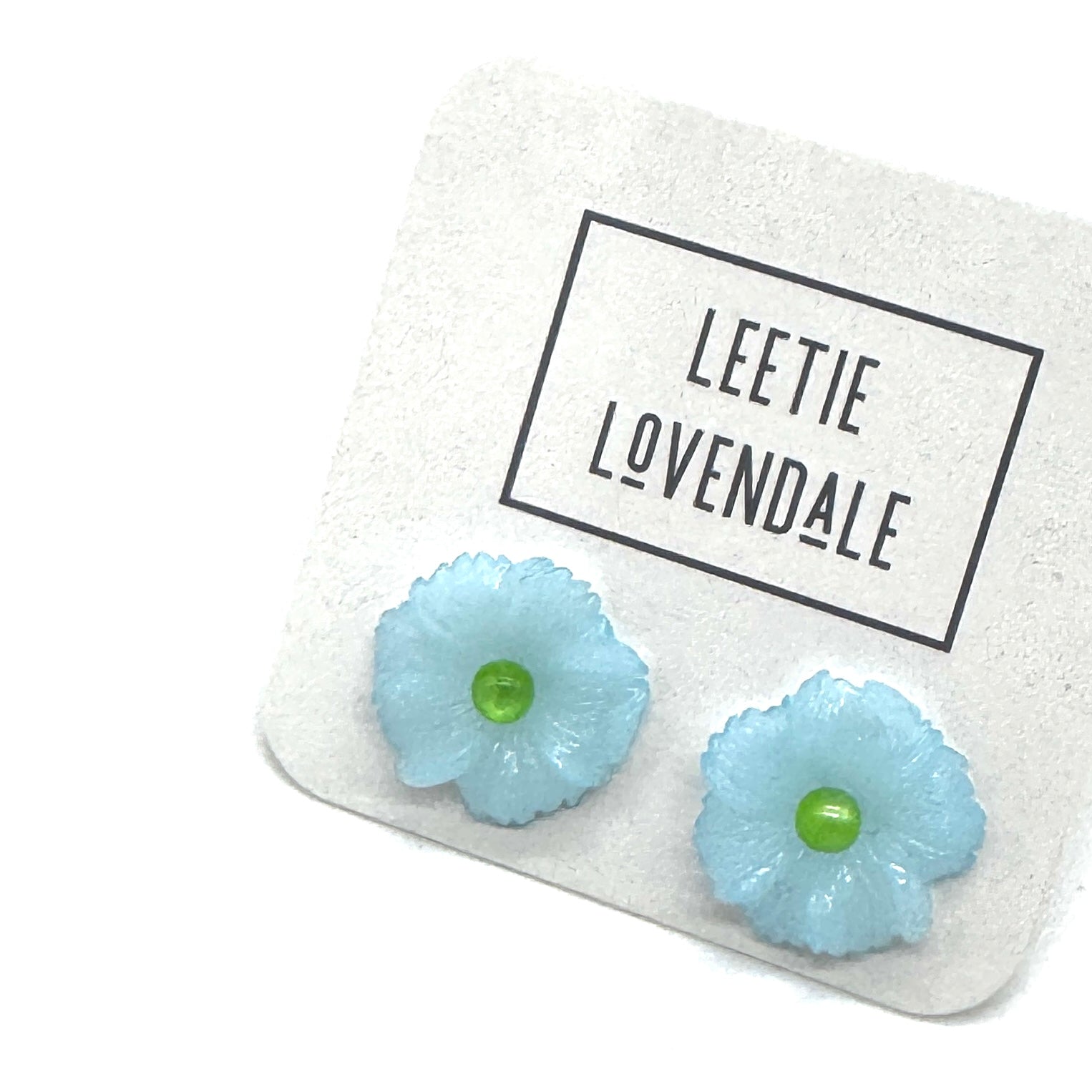 Light blue flower-shaped earrings on a card with &