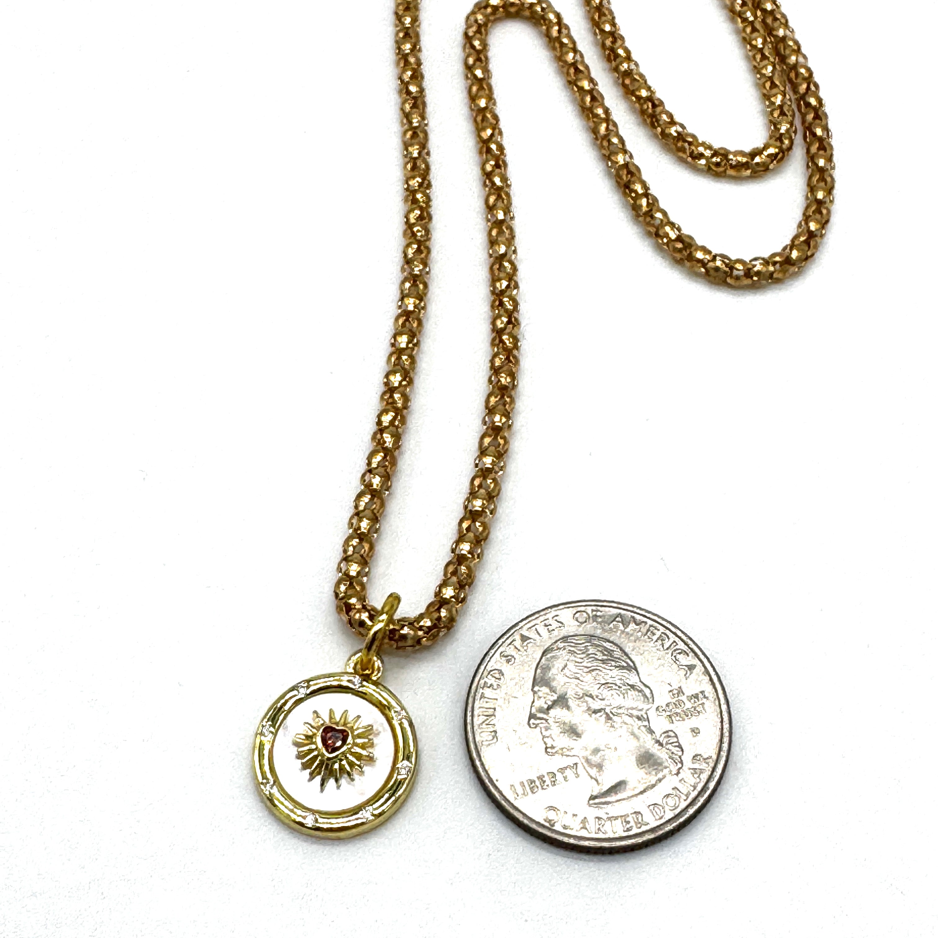 Gold necklace with a pendant and a coin on a white background