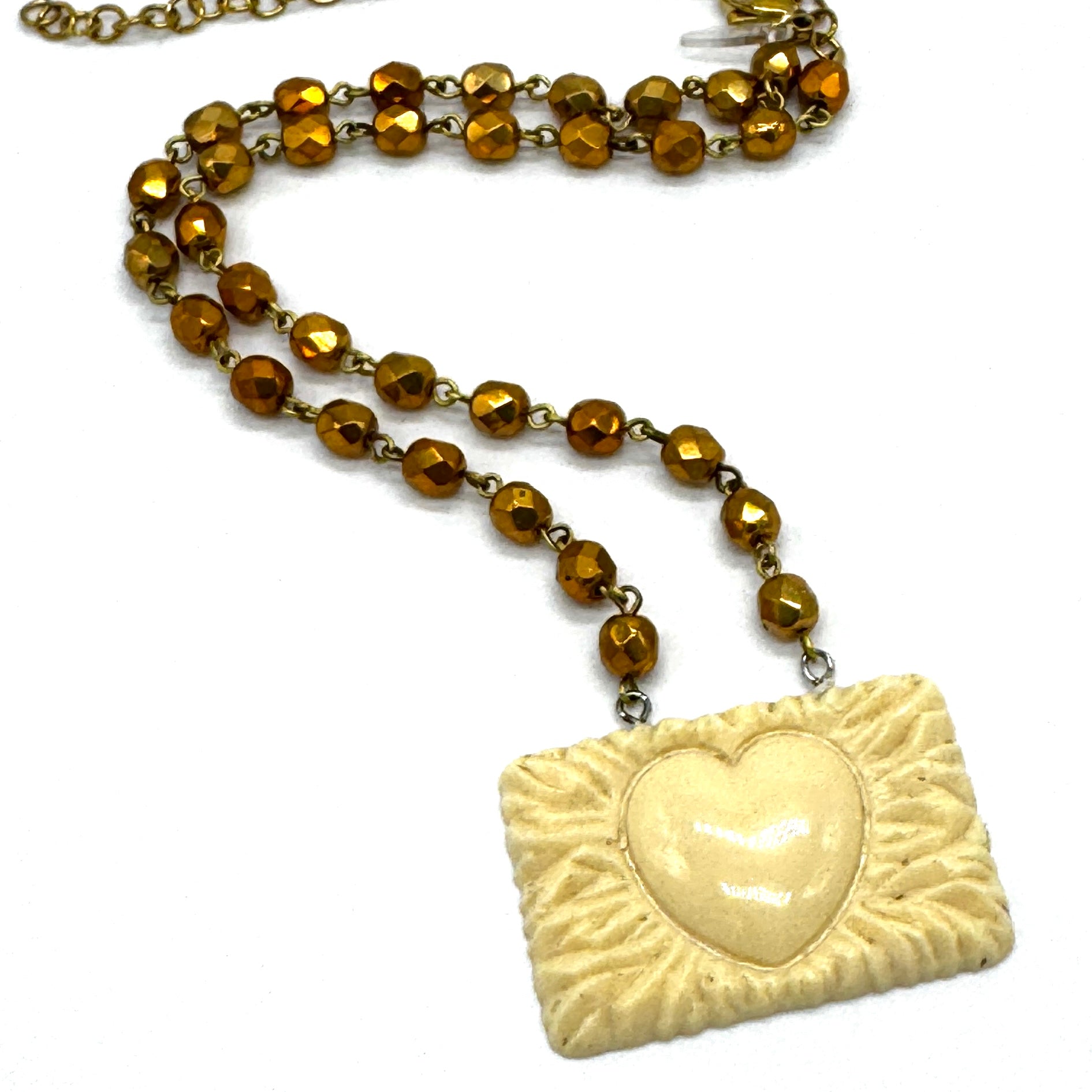 Necklace with gold beads and a heart-shaped pendant on a white background