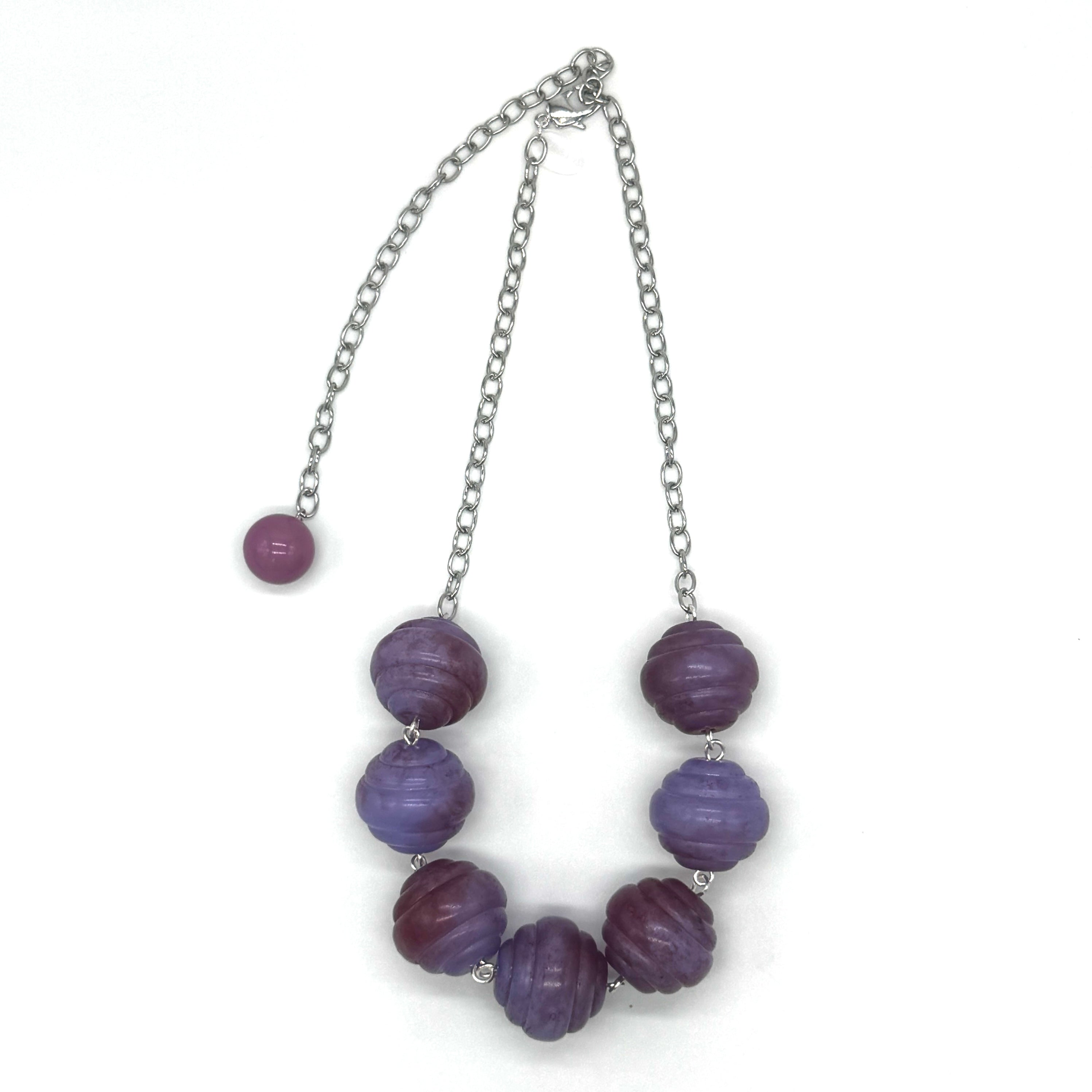 Necklace with purple beads and a silver chain on a white background
