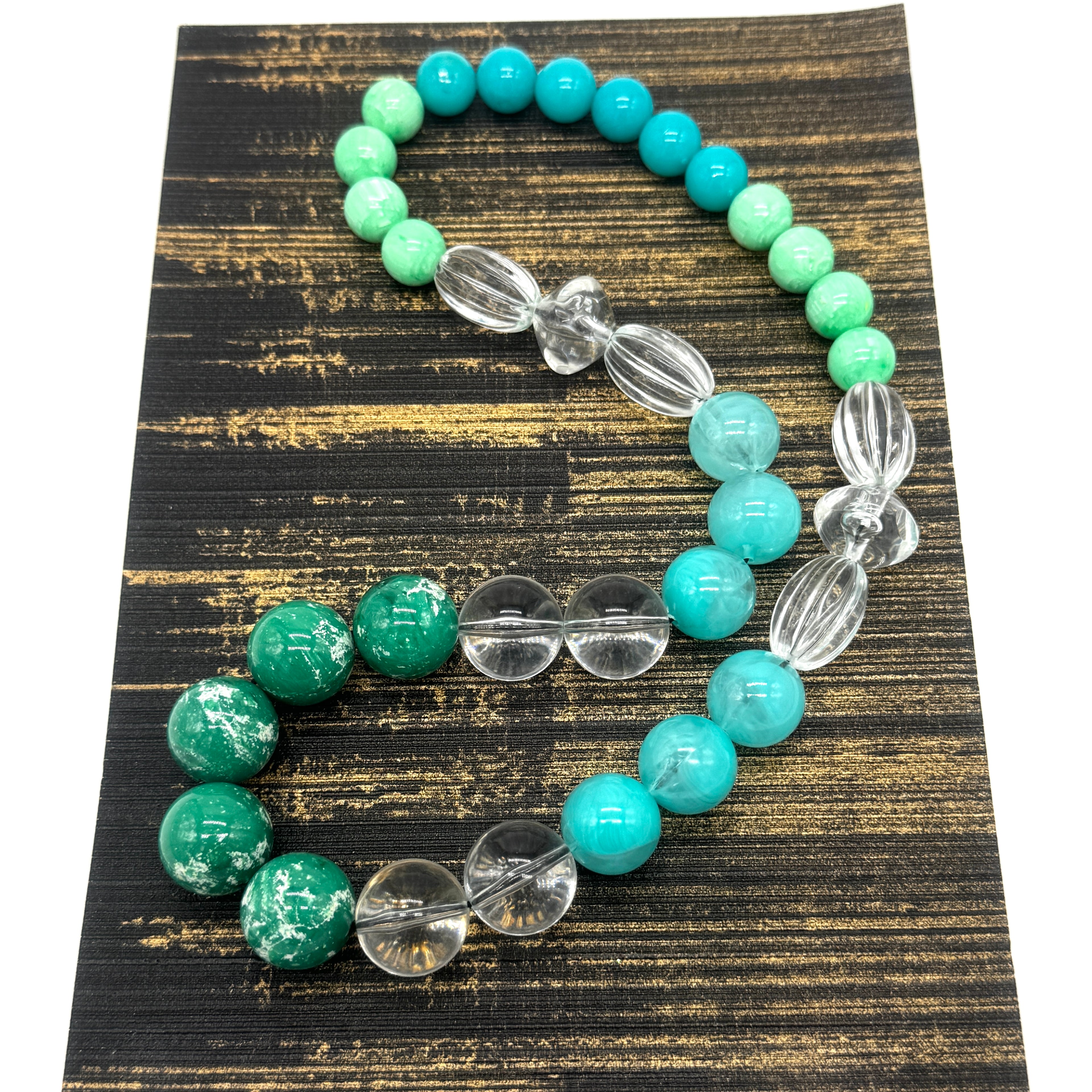Turquoise and clear beaded neckace on a textured black and gold surface