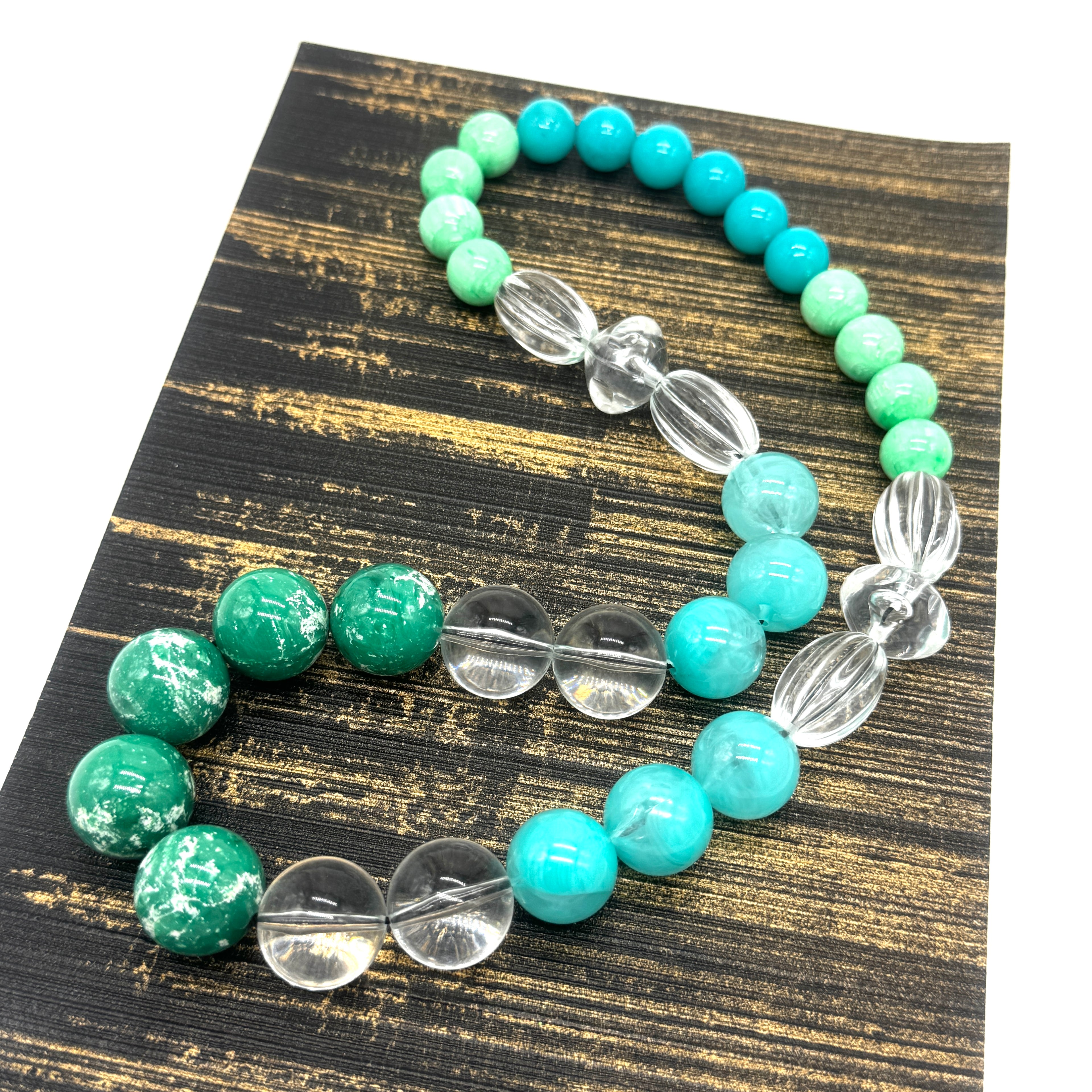 Beaded necklace with green and turquoise beads on a wooden surface