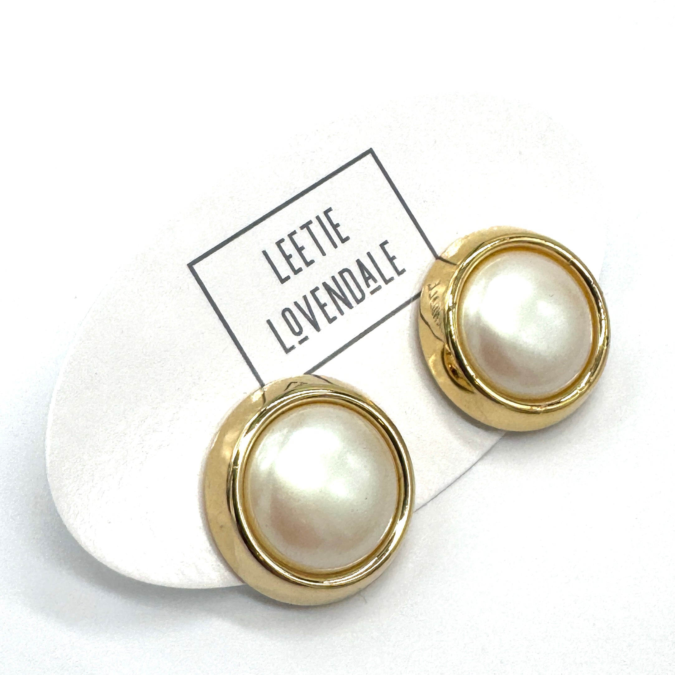 Pearl earrings with gold accents on a white background with &