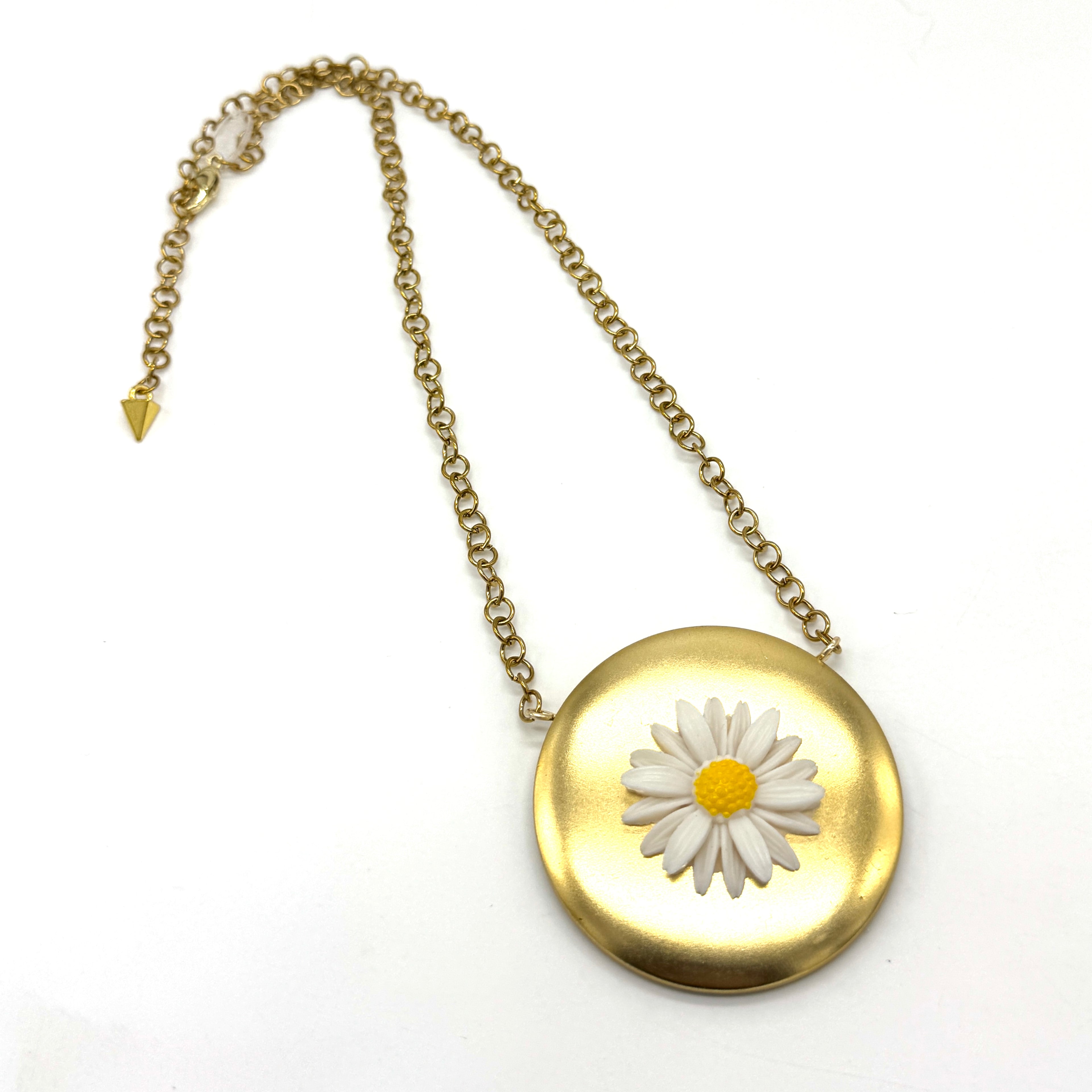 Gold tone medallion necklace with a white daisy at the center.