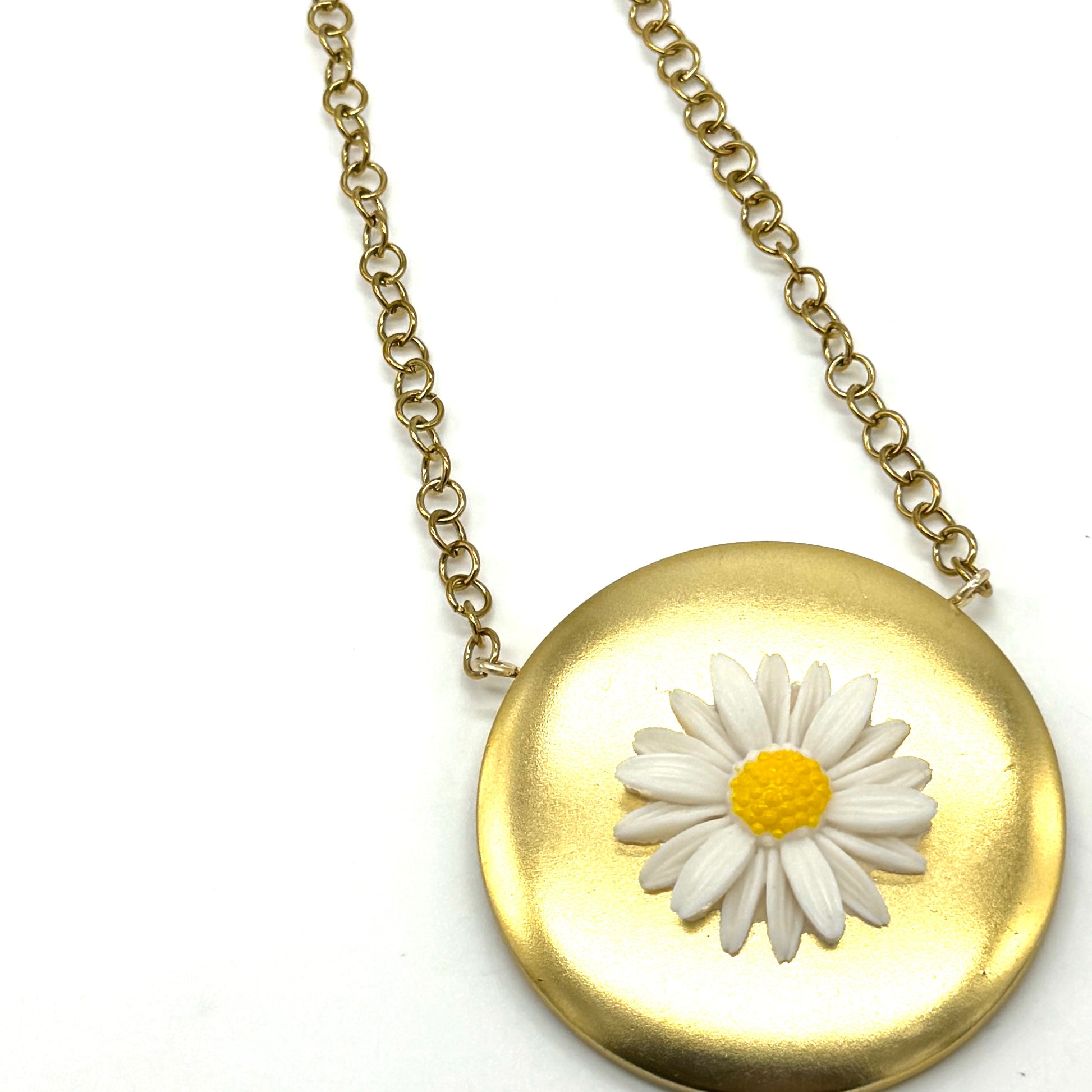 Gold tone medallion necklace with a white daisy at the center.