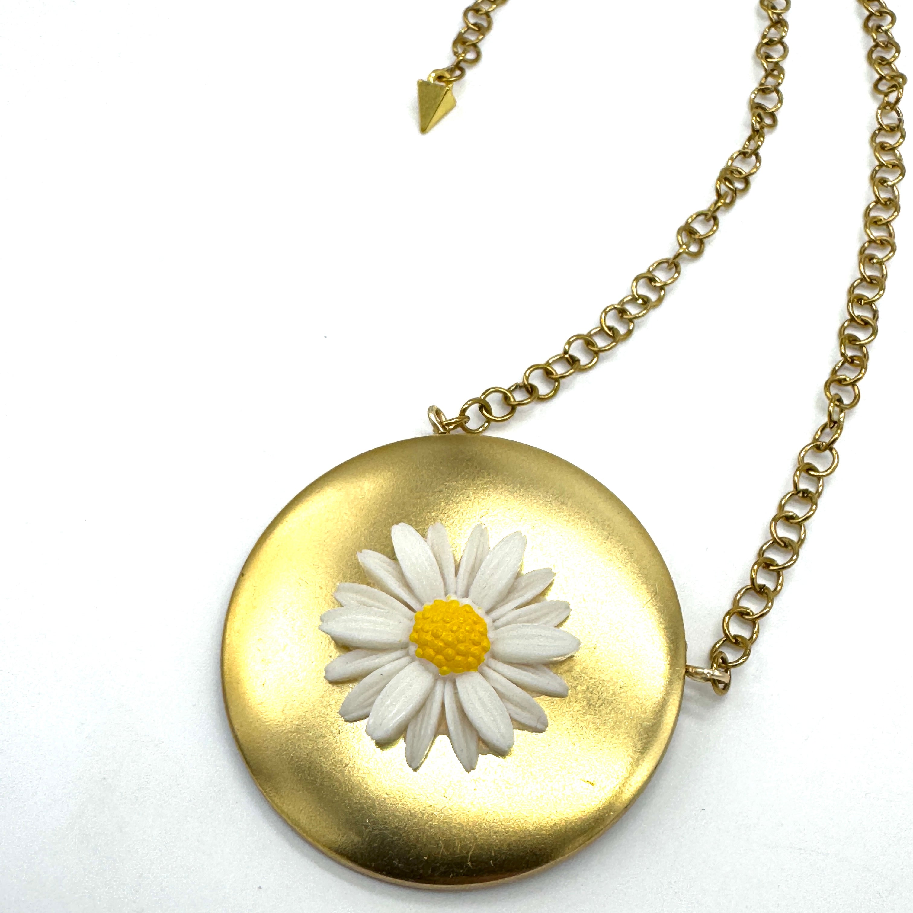 Gold tone medallion necklace with a white daisy at the center.