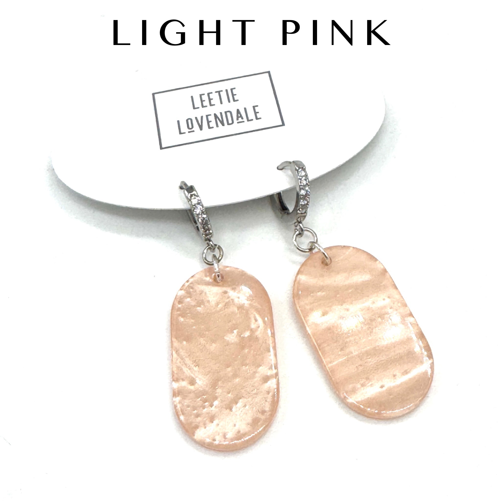Light pink earrings with silver hooks on a white background, featuring the brand &