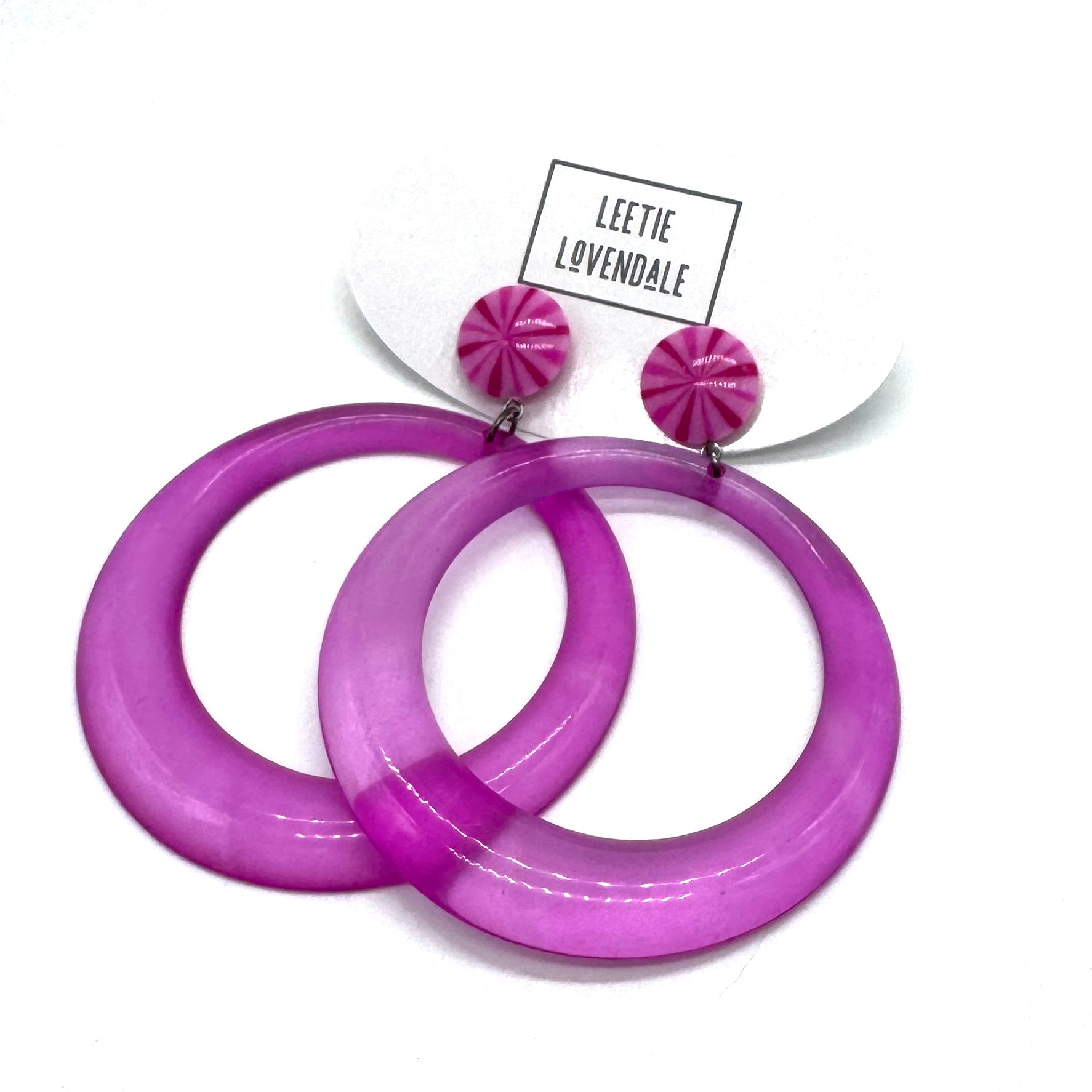 Purple hoop earrings with pink accents on a white background, featuring the brand &
