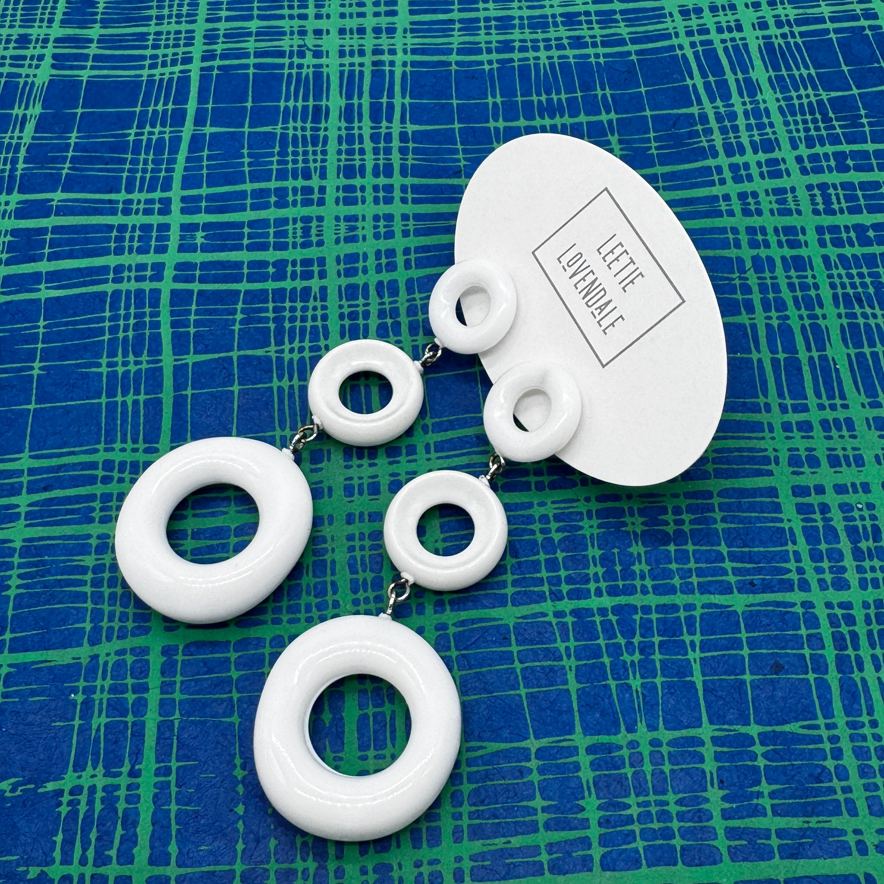 White circular earrings on a blue and green checkered background