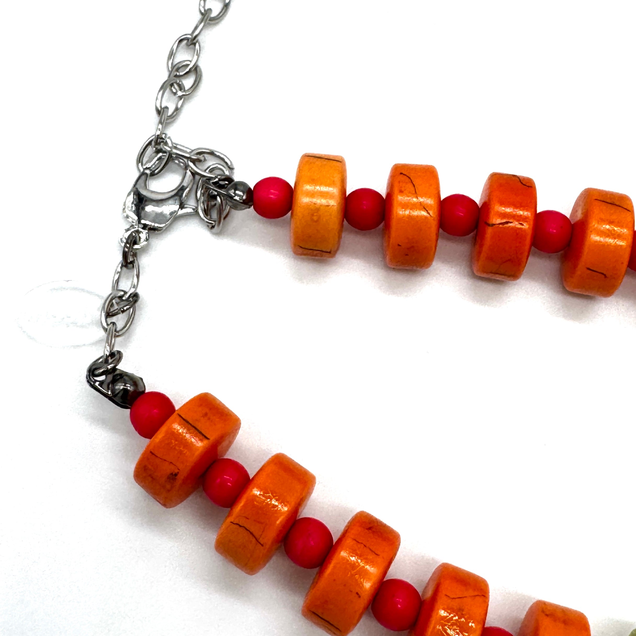 Bracelet with orange and red beads on a white background