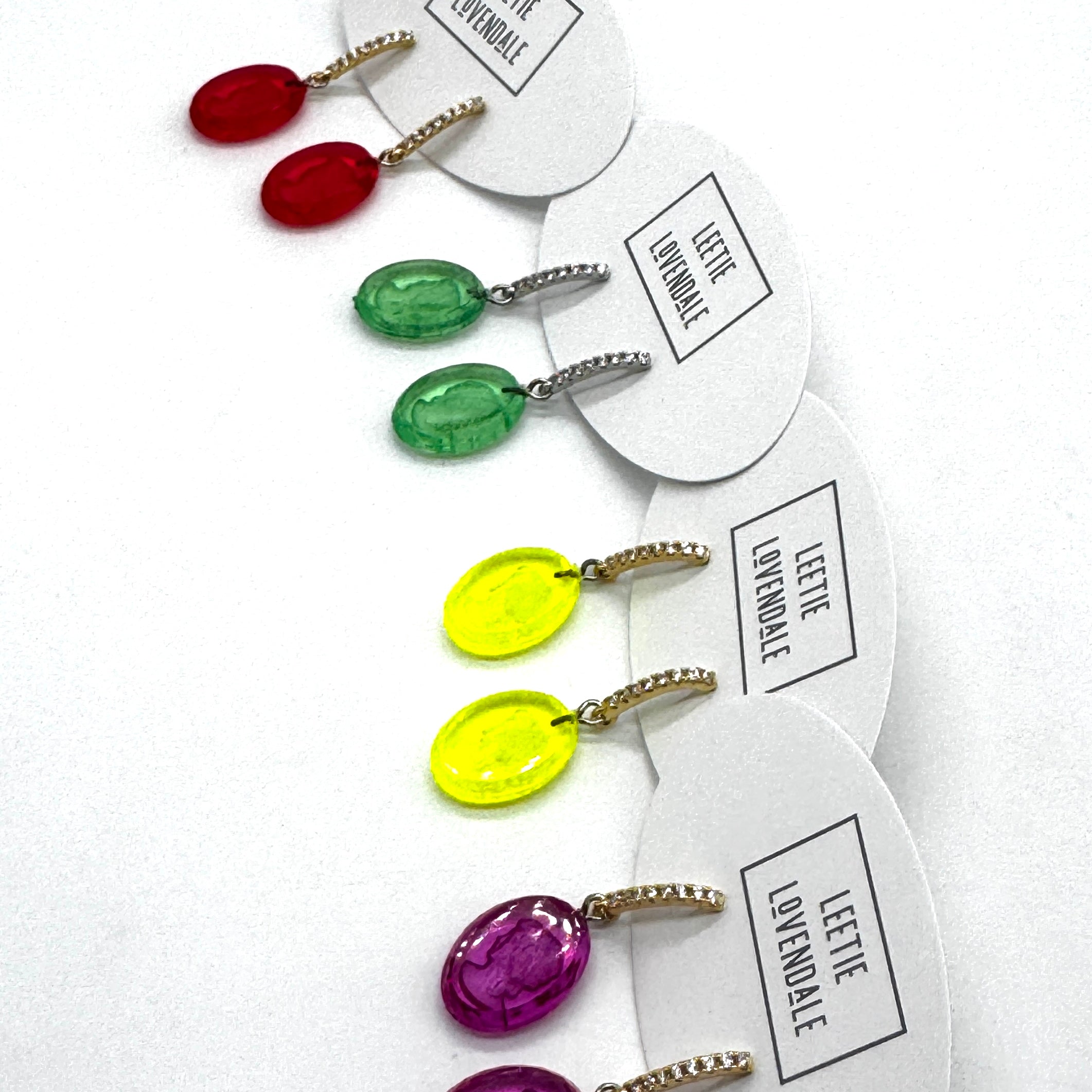 Colorful earrings on white cards with &