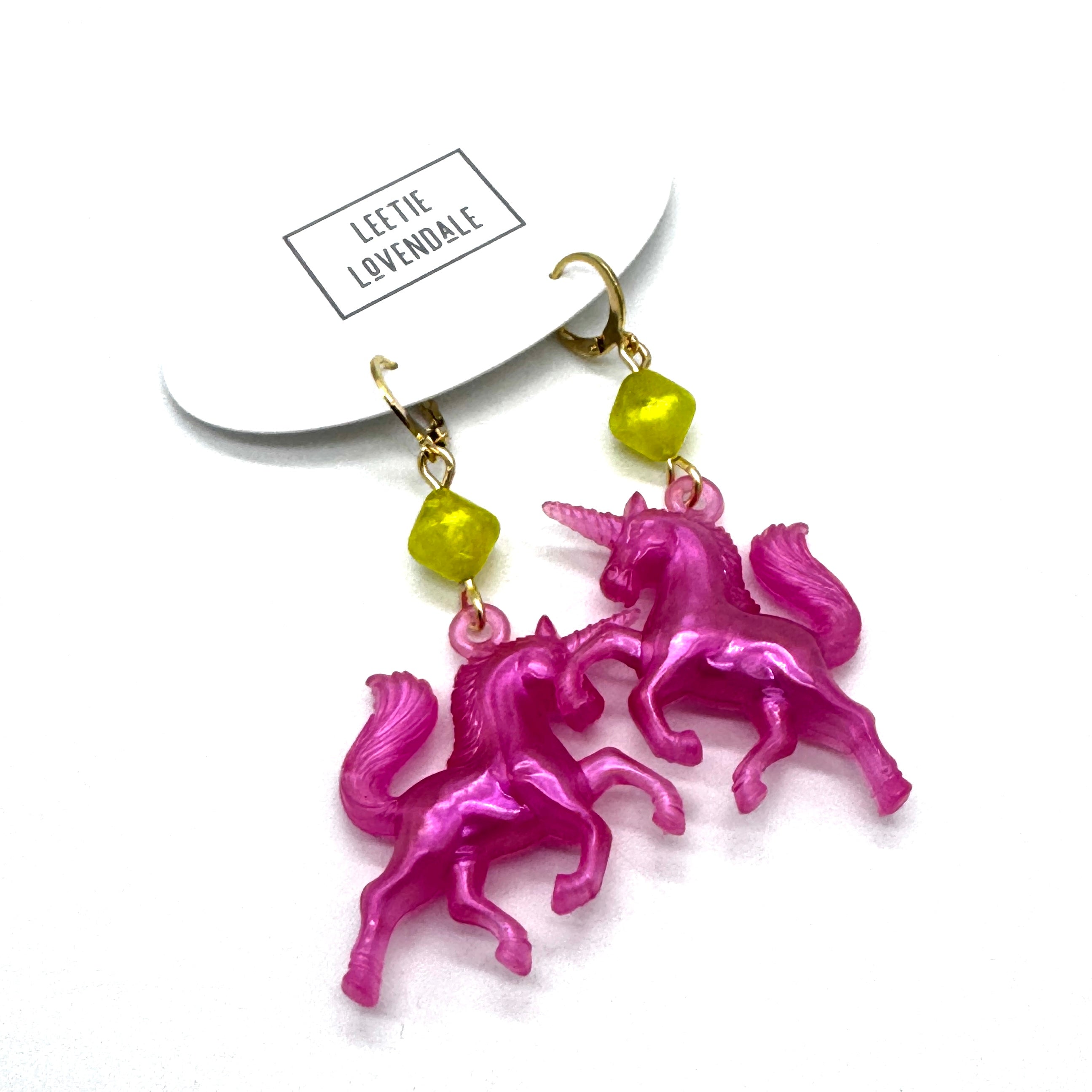 Pink unicorn earrings with green beads on a white background