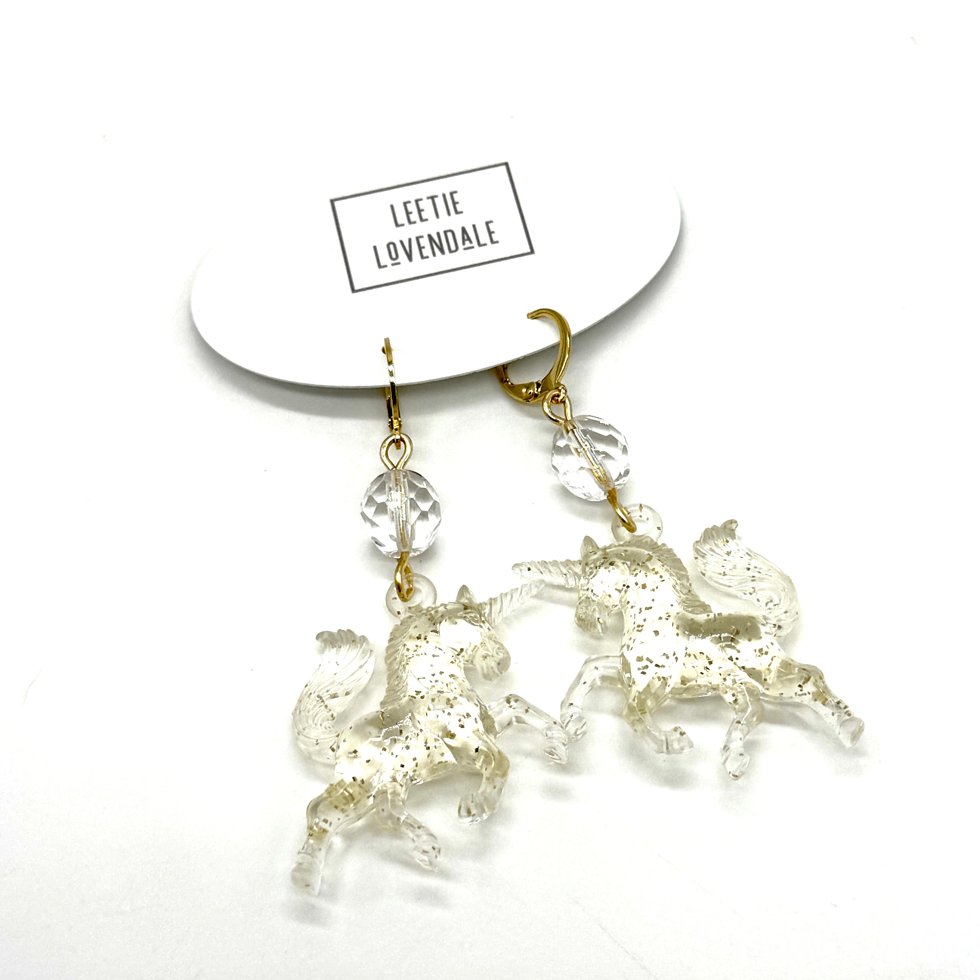 Unicorn-shaped earrings on a white background with &