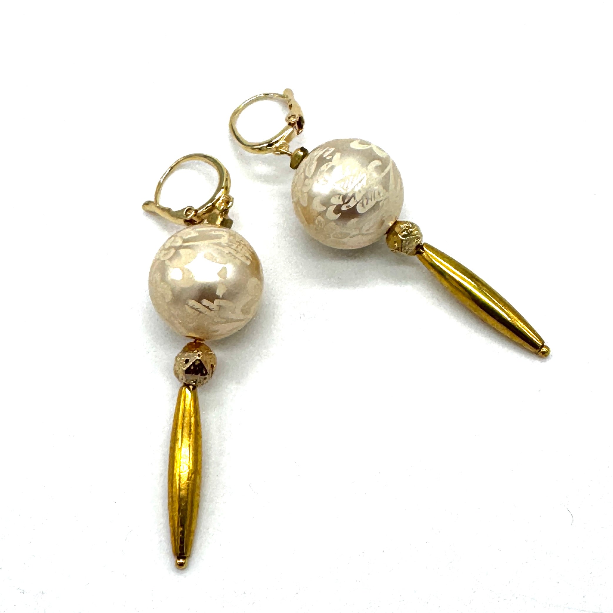 Dangle earrings with floral cream colored beads and golden accents on a white background.