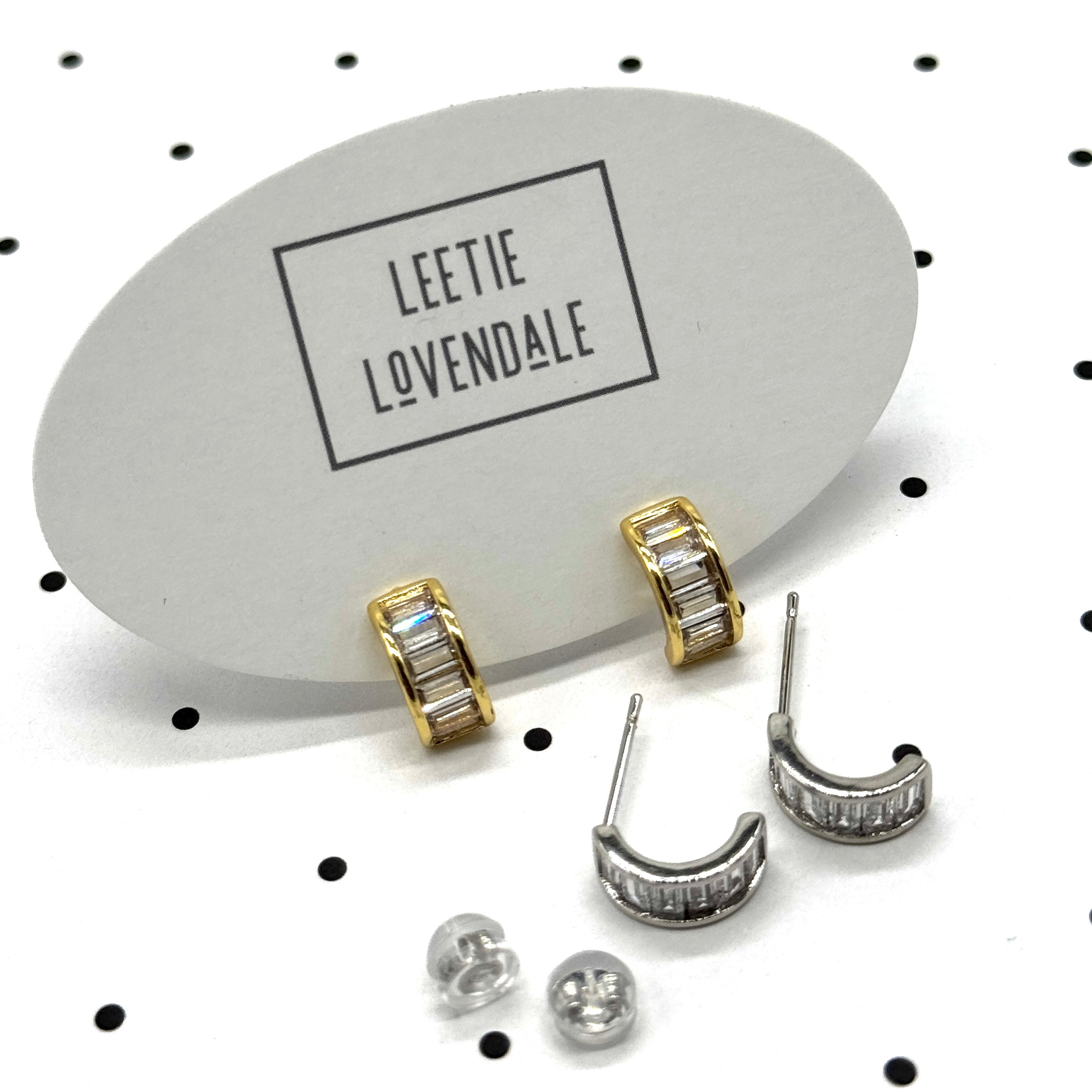 Silver and gold crystal hoop earrings on branded earring cards.