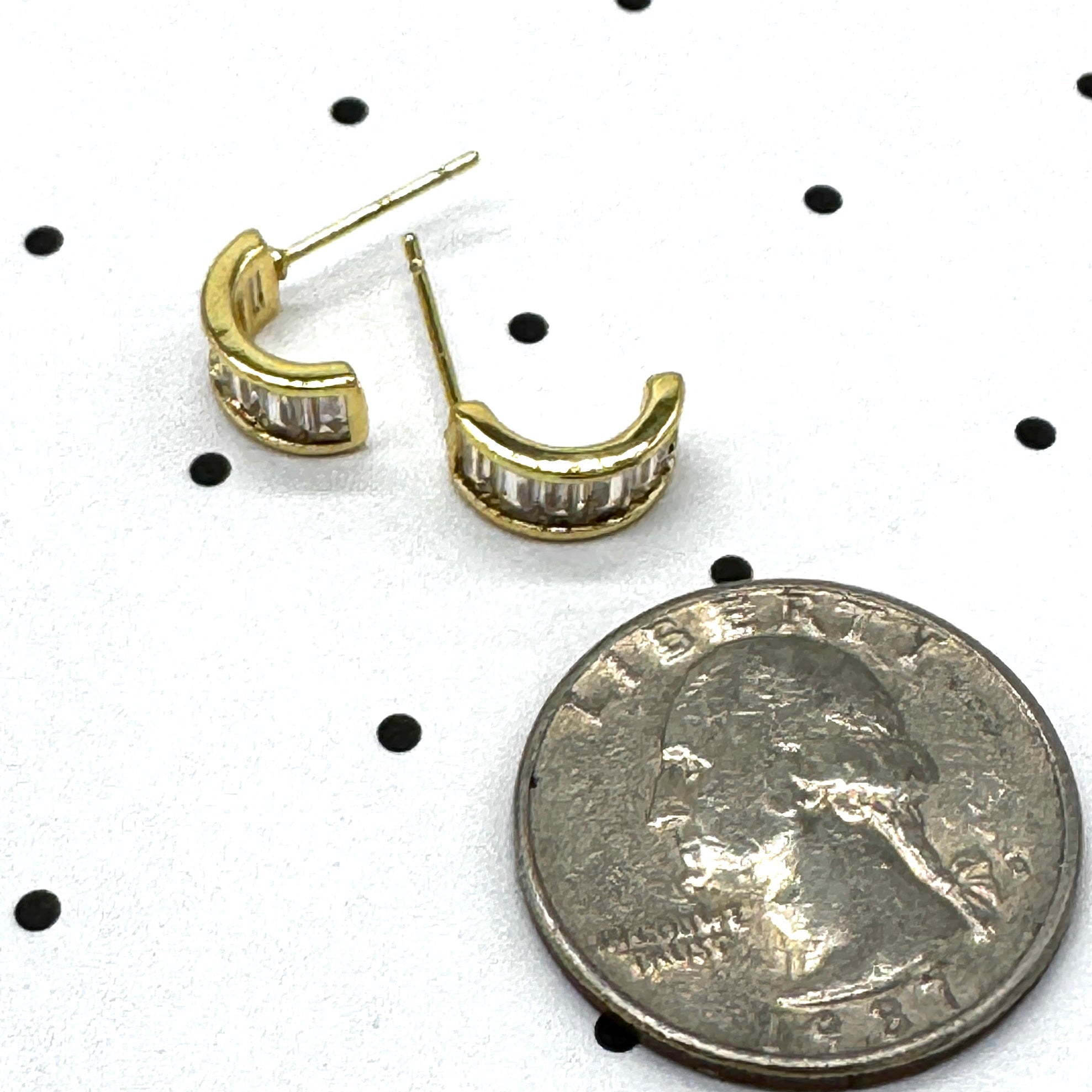 Gold and crystal hoop earrings on a polka dot background with a quarter for scale.