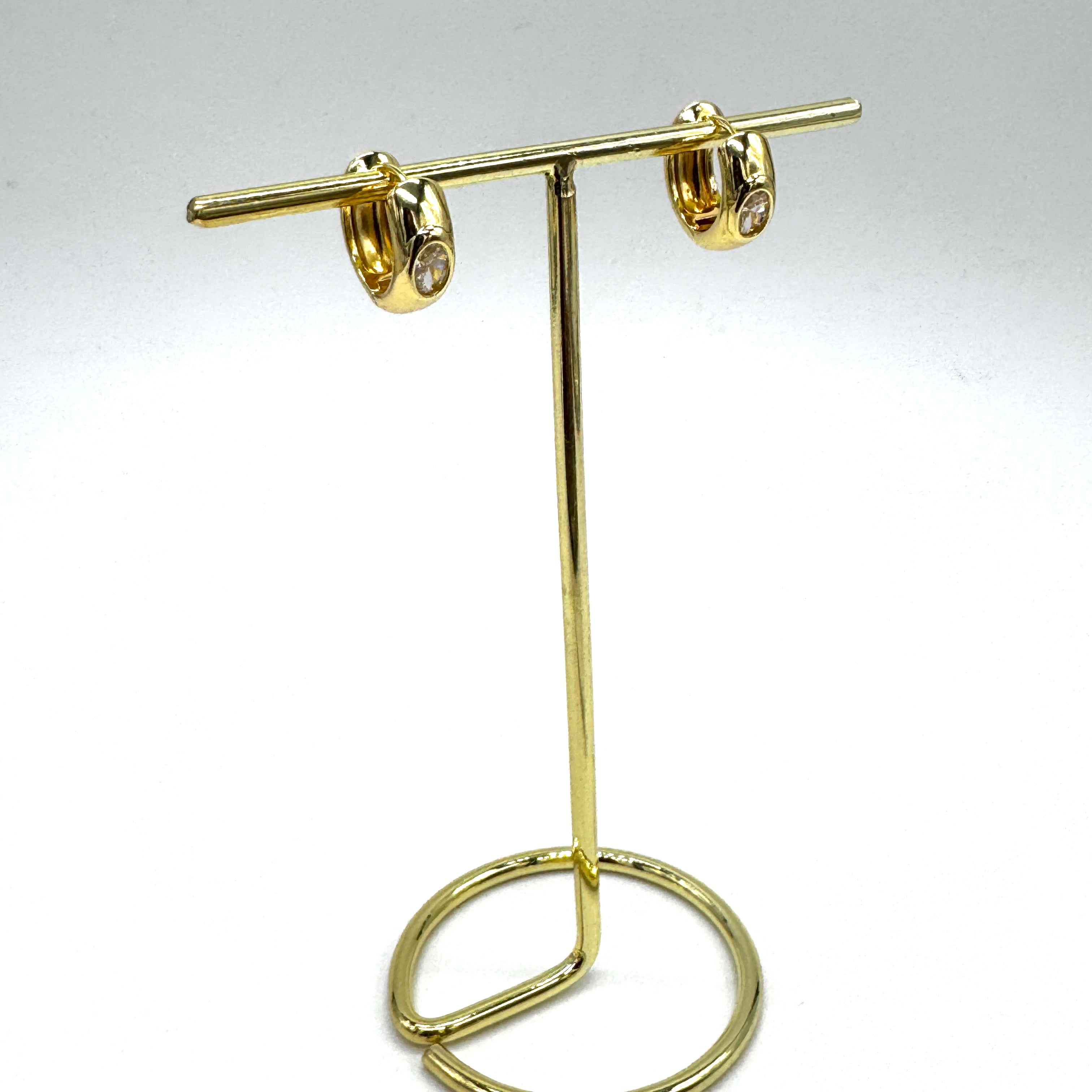 Gold and crystal hoop earrings on a gold stand.