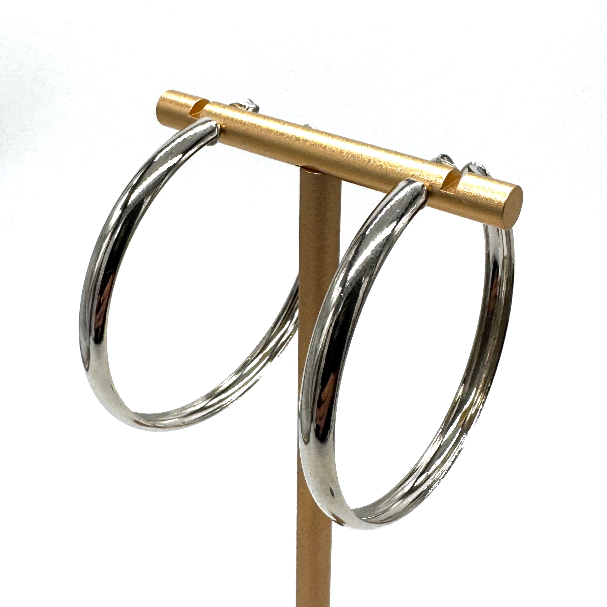 Large silver hoop earrings on a gold stand.