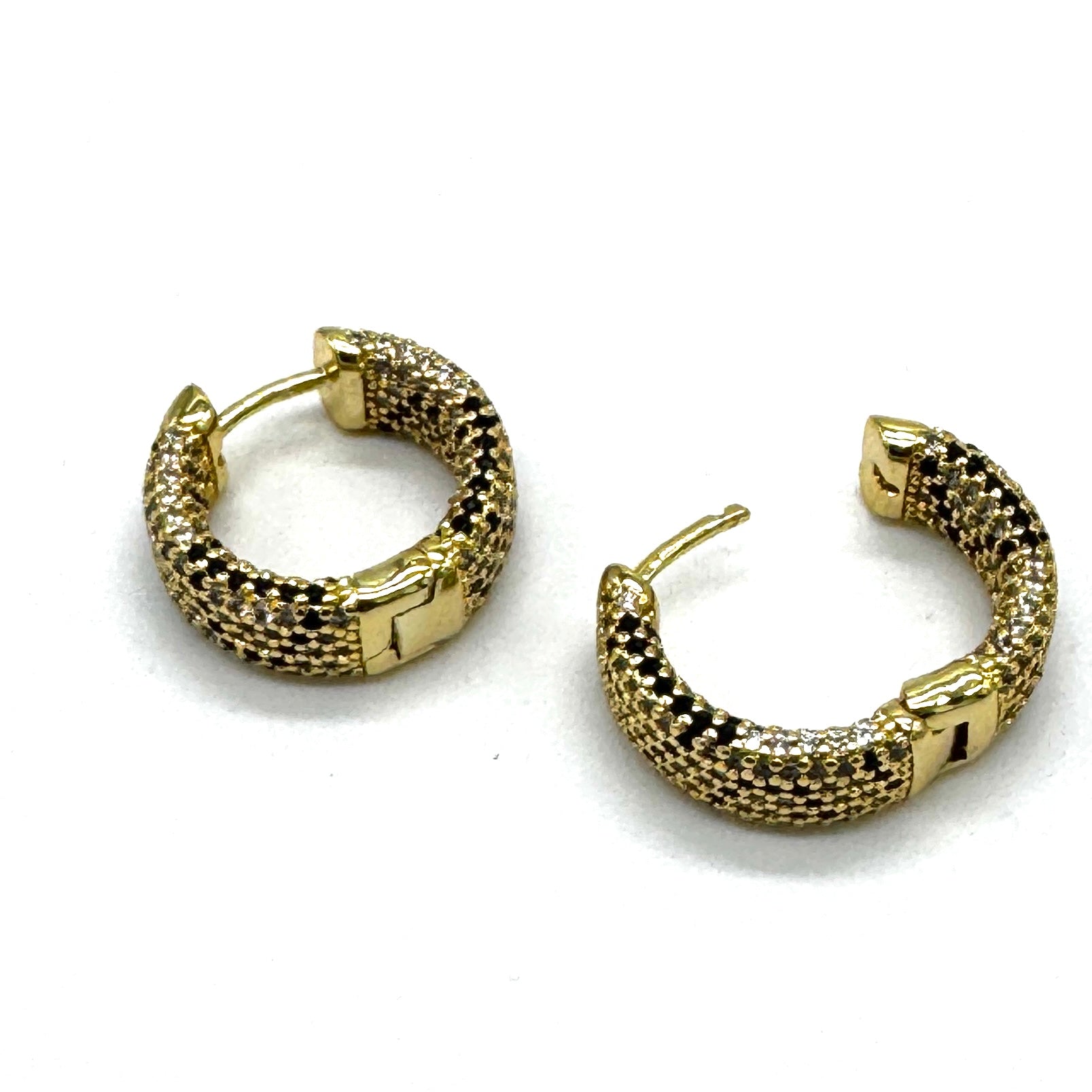 A pair of gold hoop earrings with a textured, woven pavƩ-style design, displayed on a clean white background.