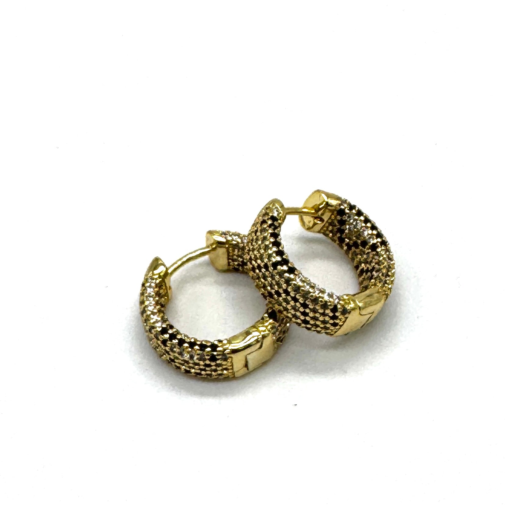 A pair of gold huggie hoop earrings with a textured, pave-like chain pattern, displayed on a clean white background.