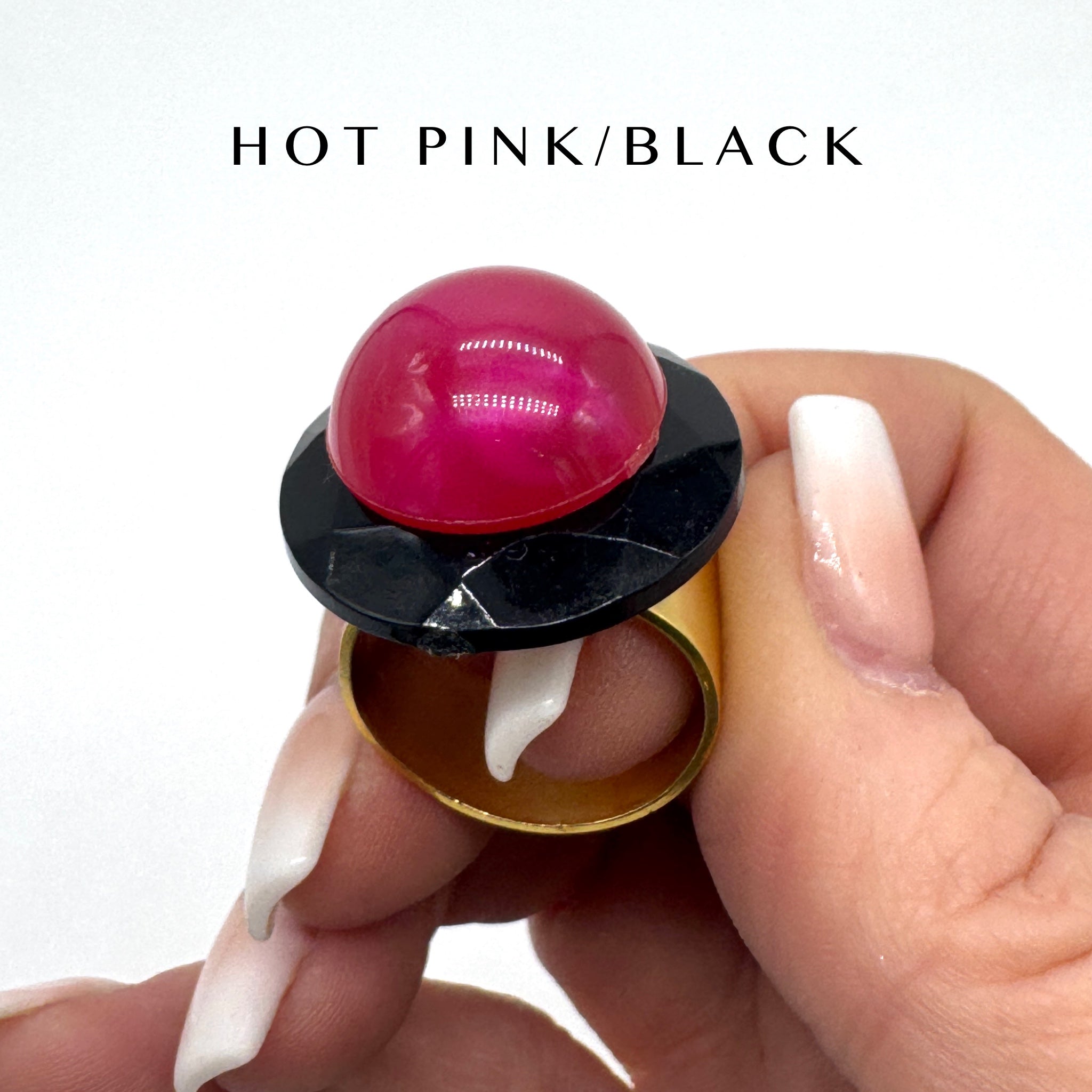 Hand holding a lip balm with a pink cap and black top, labeled &