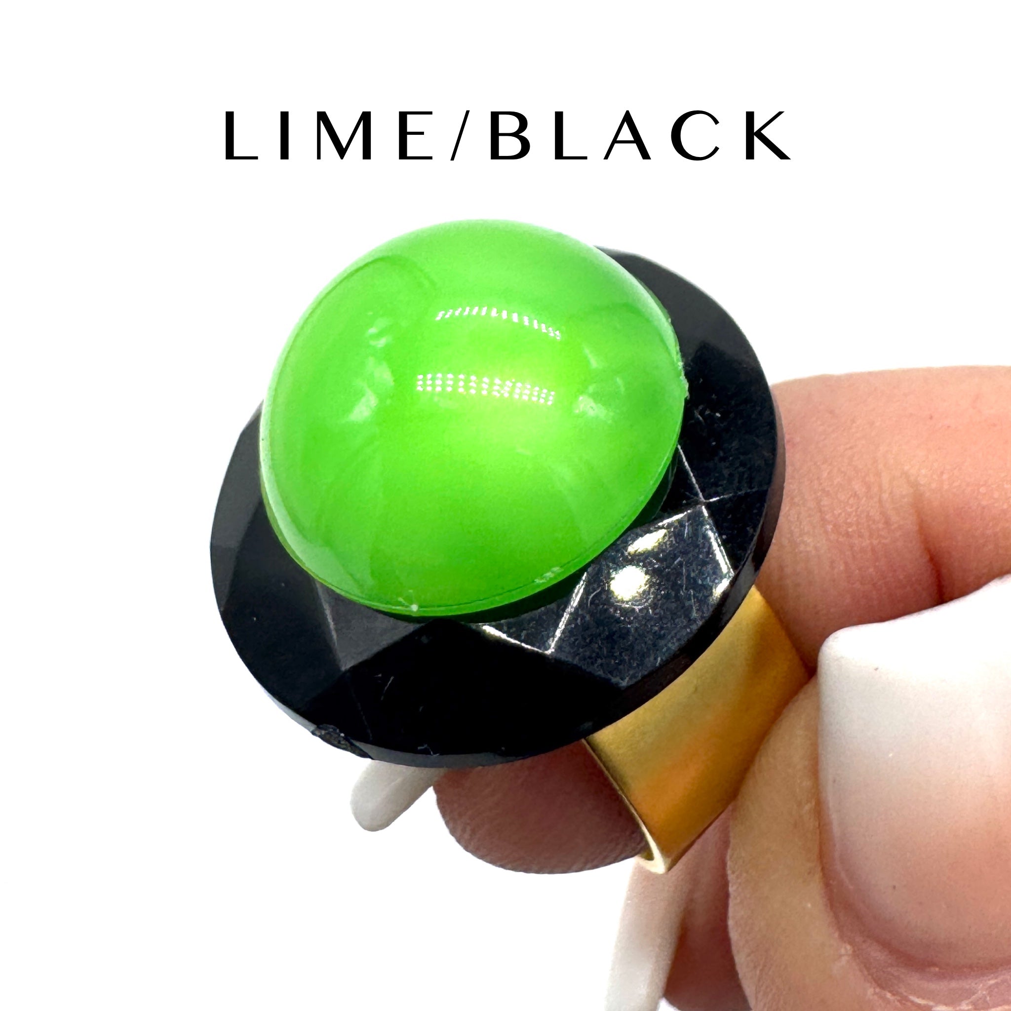 Green and black ring held by a hand with &