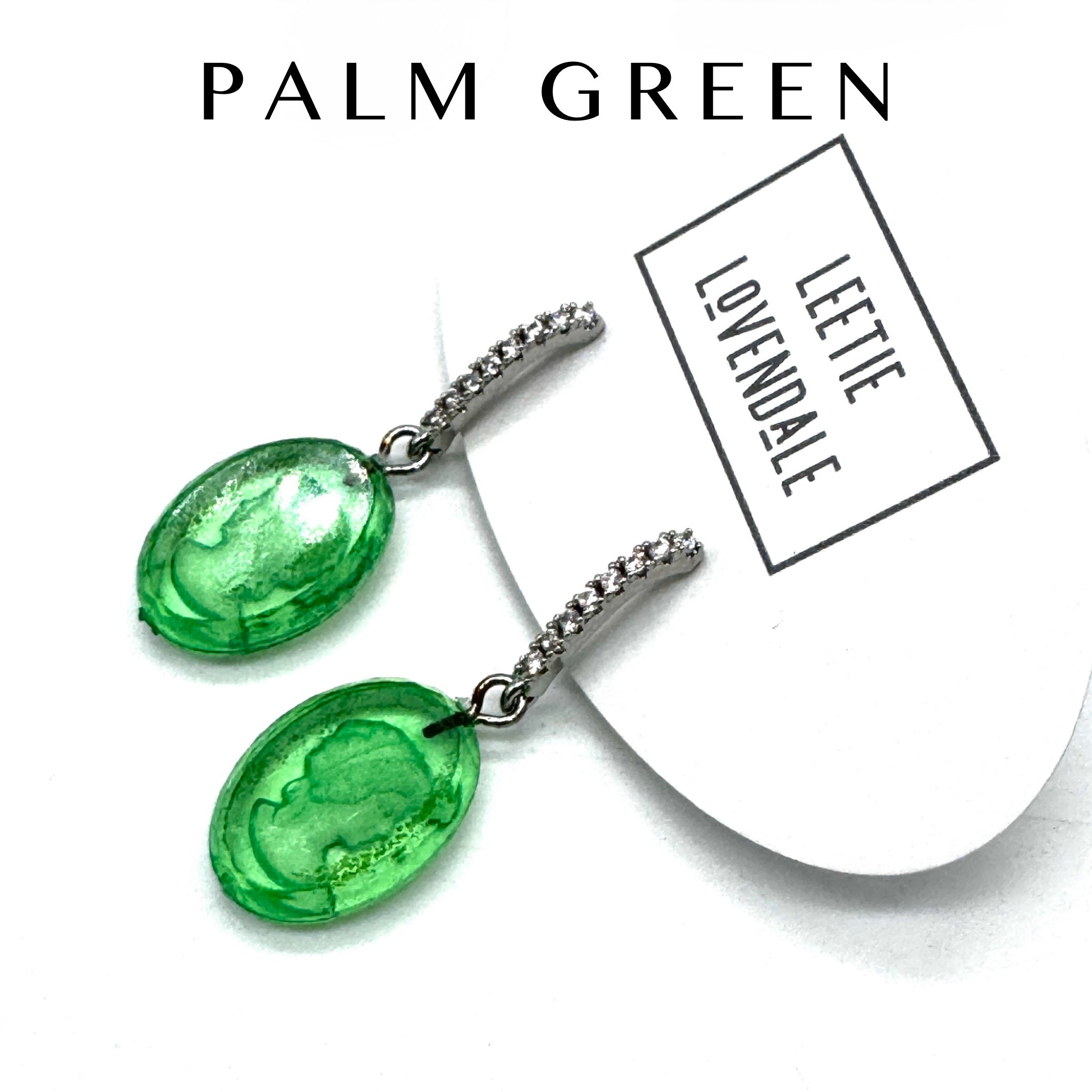 Green earrings with a white card displaying &