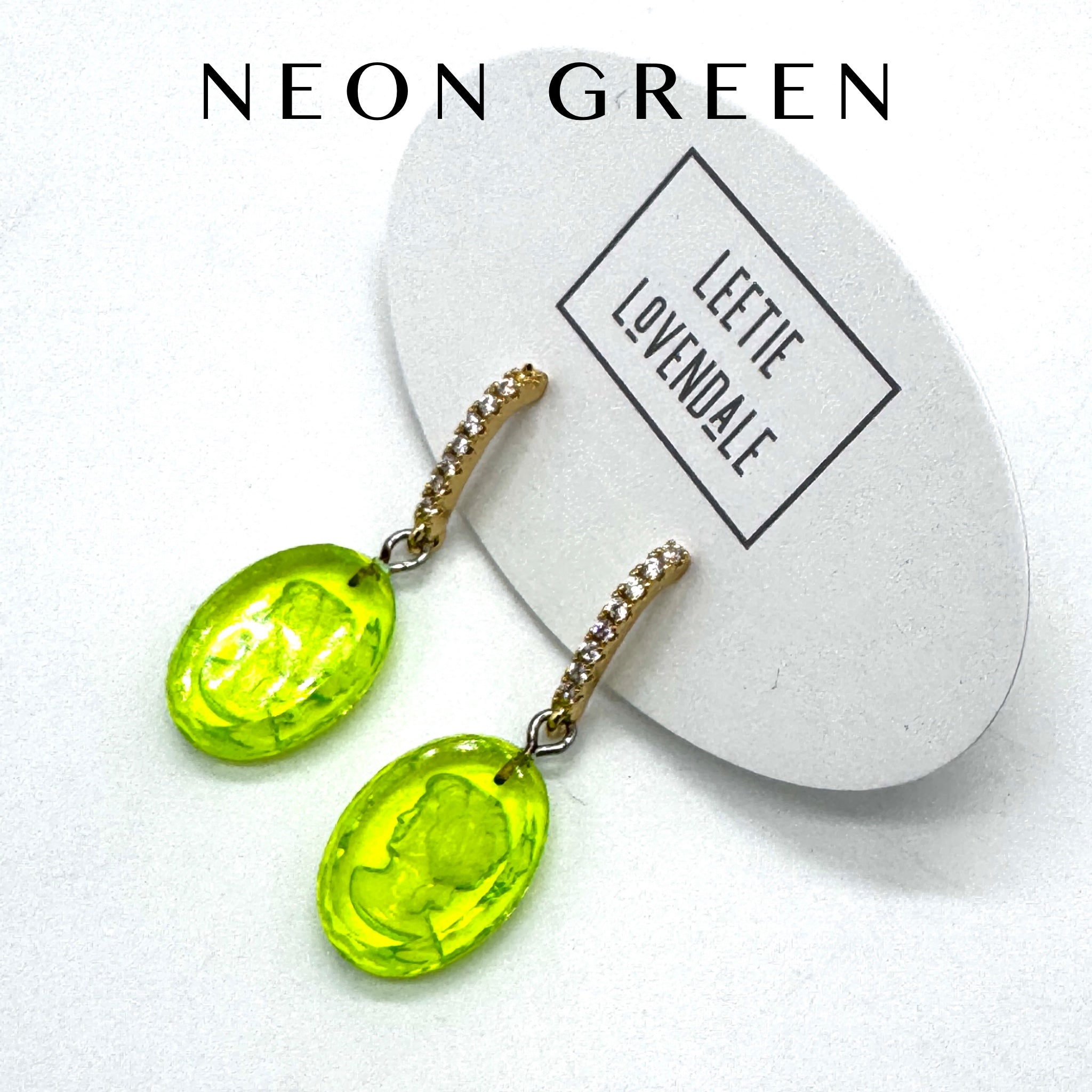 Neon green earrings on a white card with &