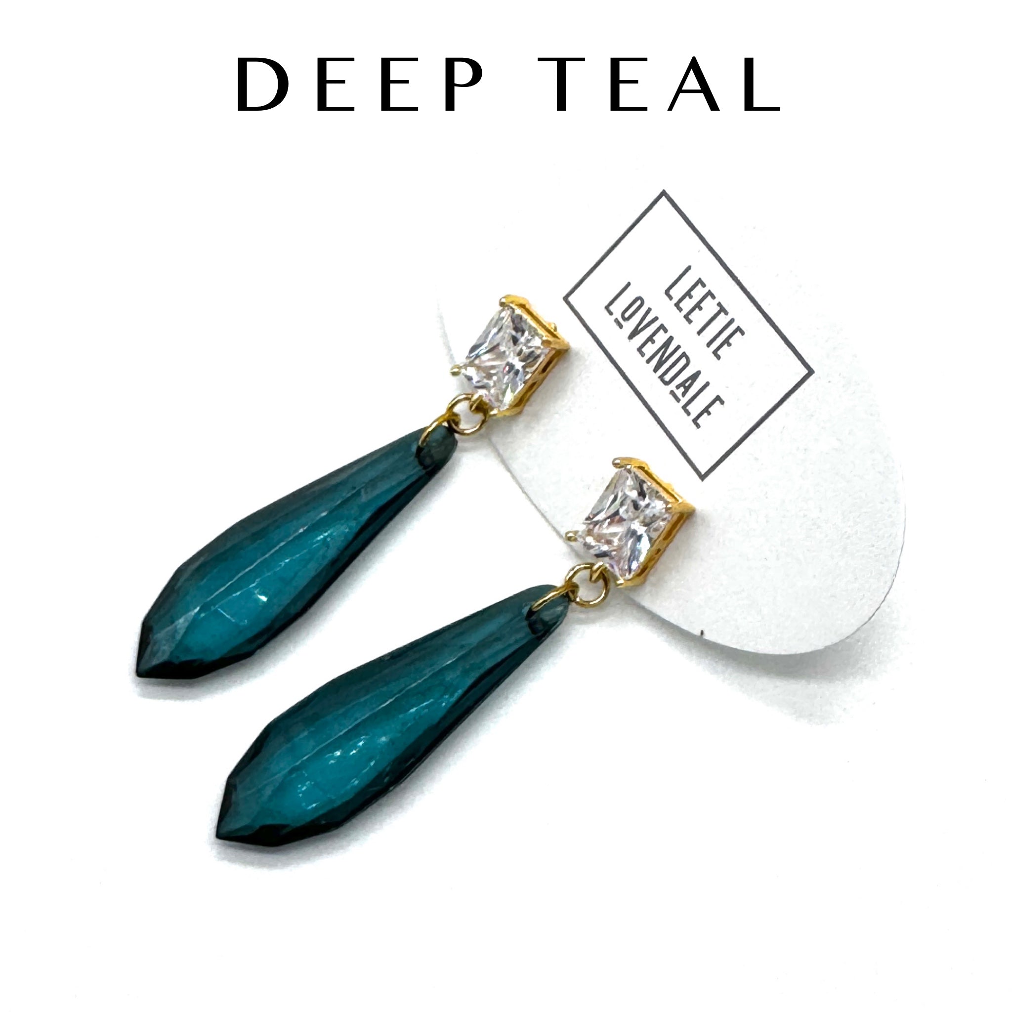 Teal earrings with gold accents on a white background, featuring the brand &