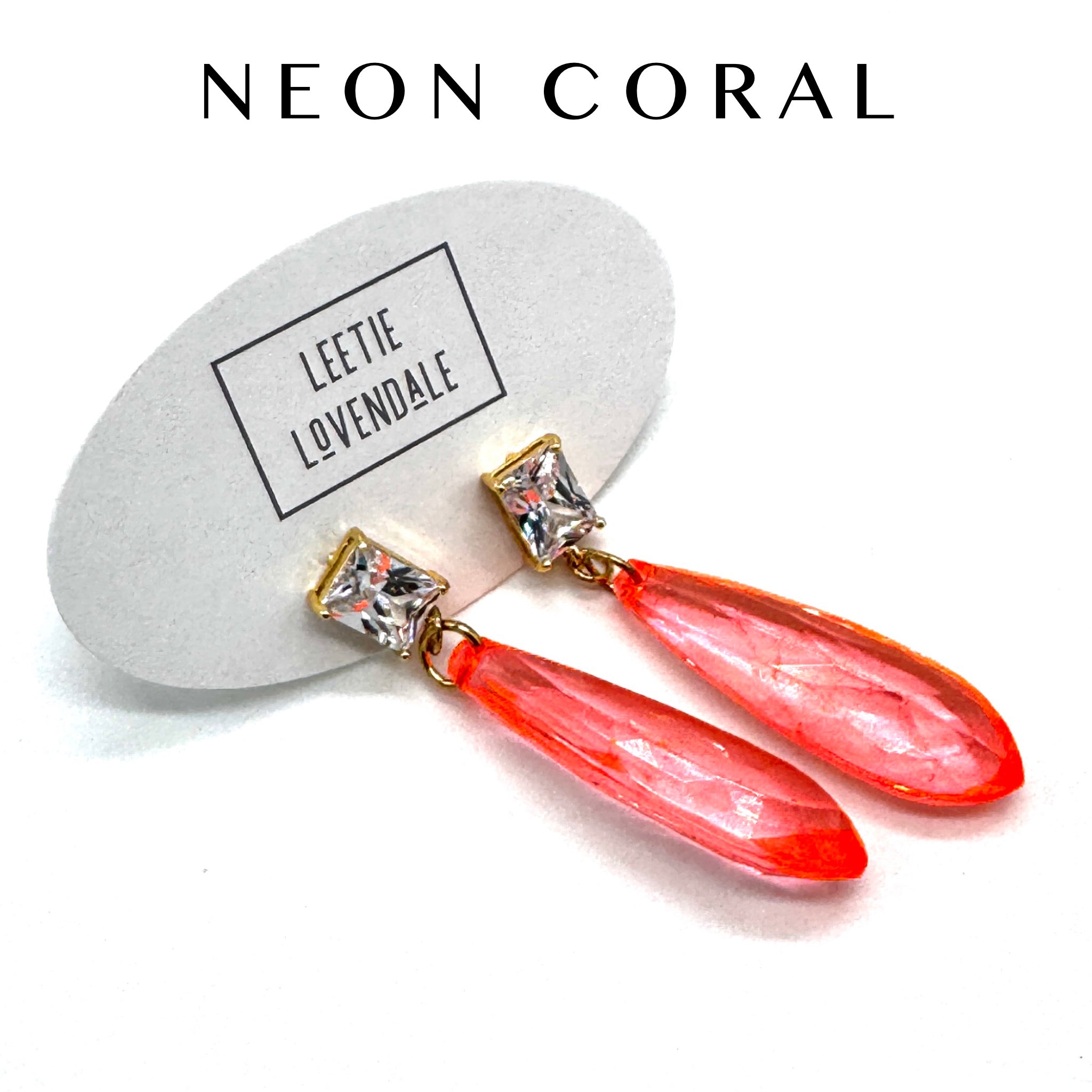 Neon coral earrings with crystal accents on a white background, featuring the brand &