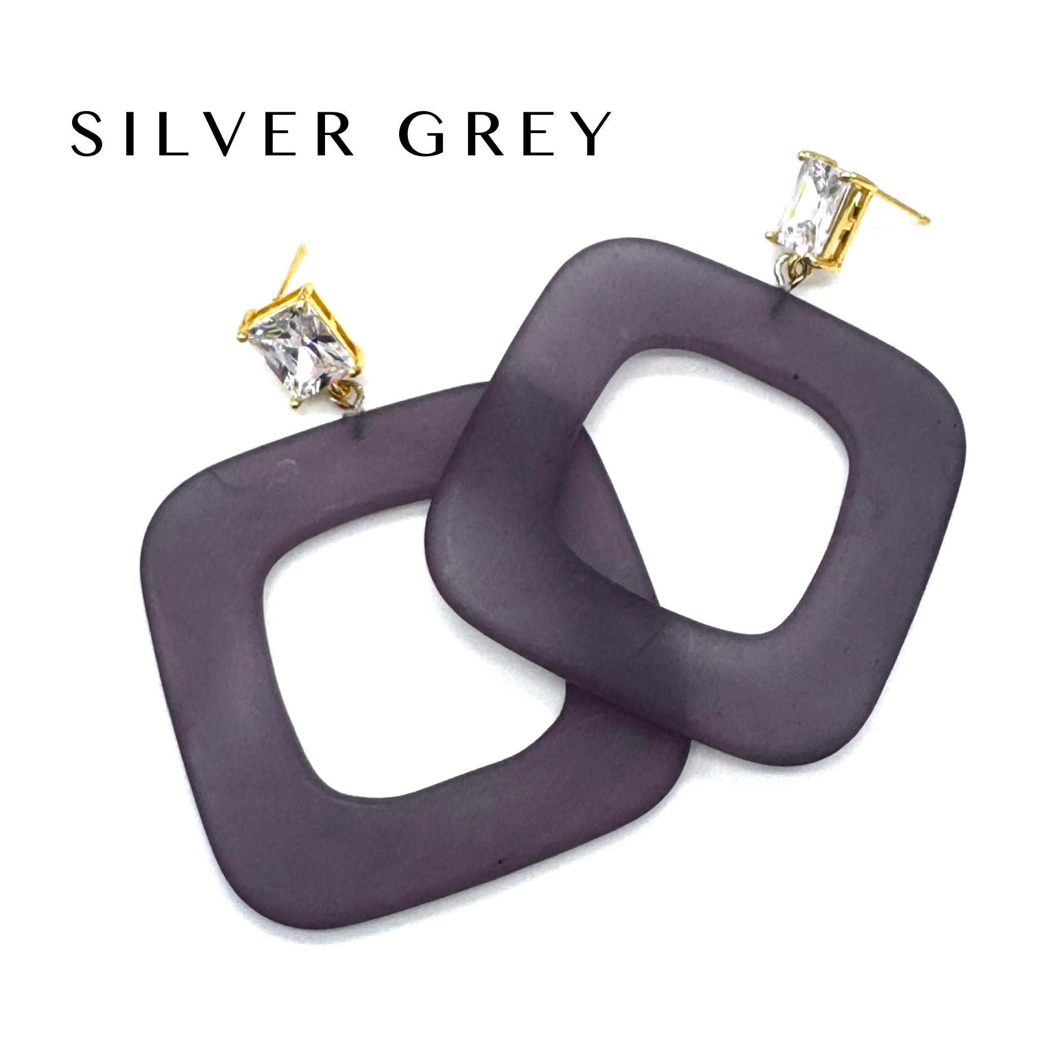 Square open-frame dangle earrings in a dark greyish-purple color with gold-tone posts and clear rhinestones, shown on a white background with the text &